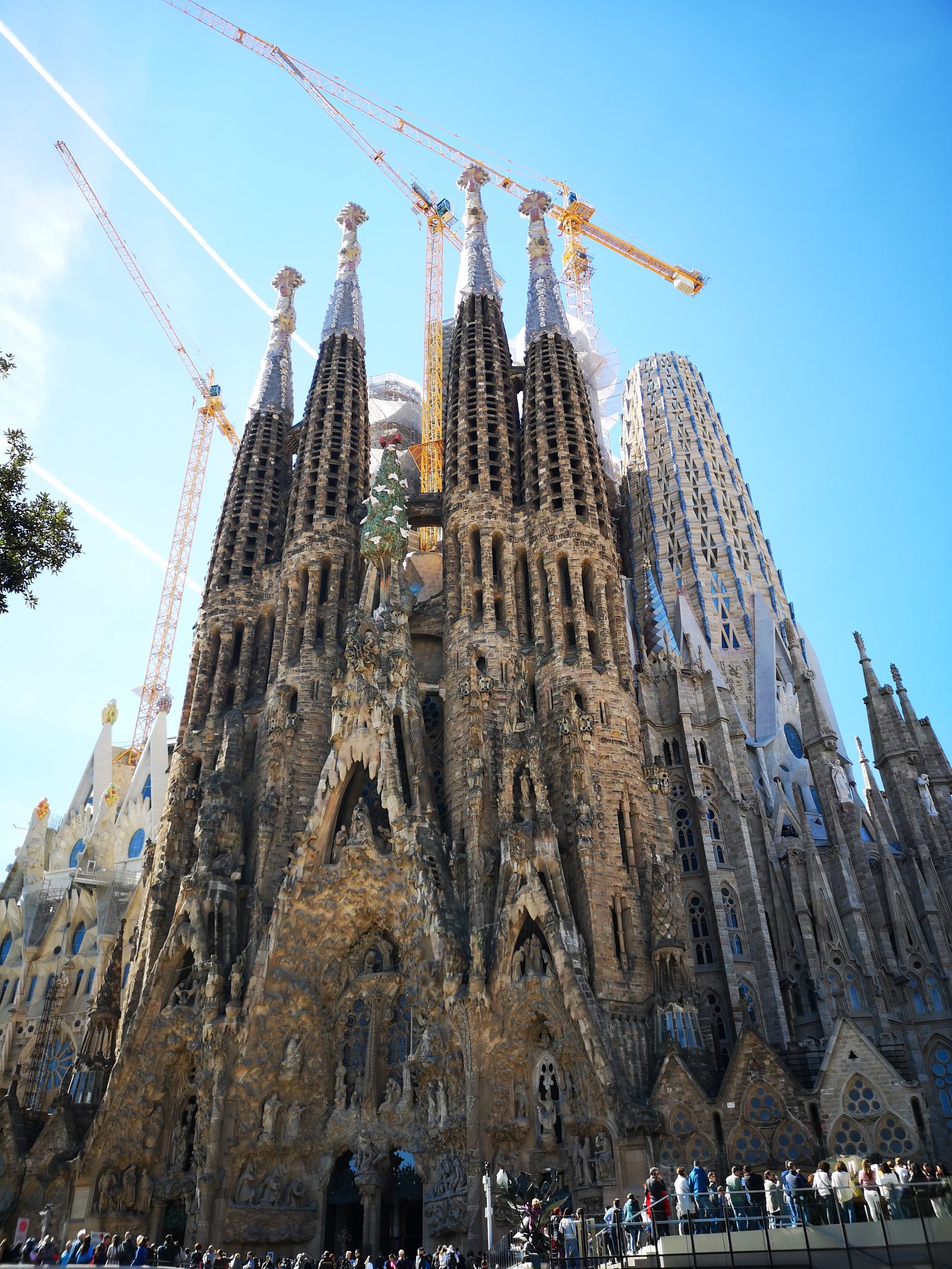 Fachada del Nacimiento de la Sagrada Familia con torres y grúas de construcción.