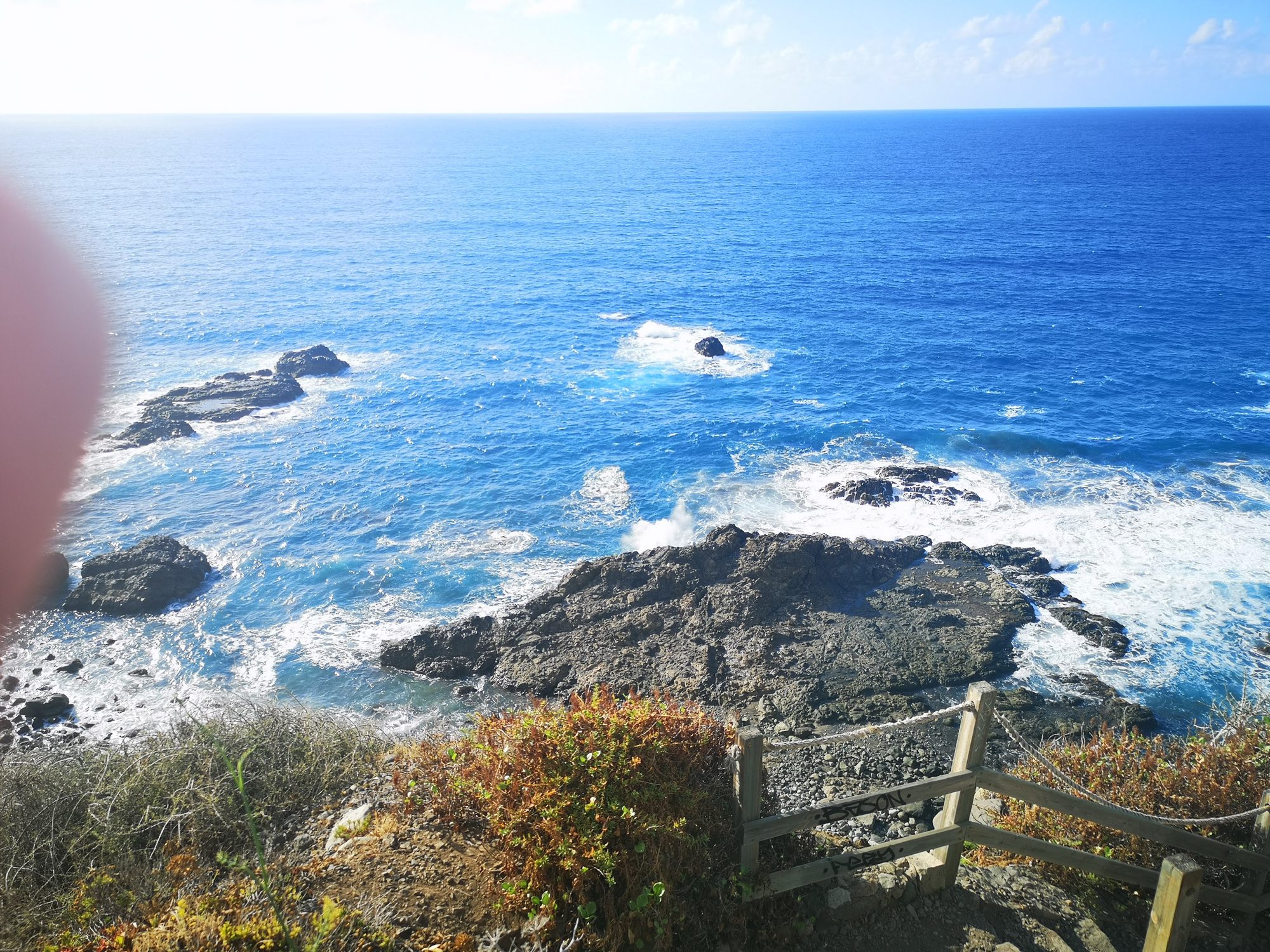 Vista del océano Atlántico azul chocando contra rocas volcánicas en la costa escarpada.