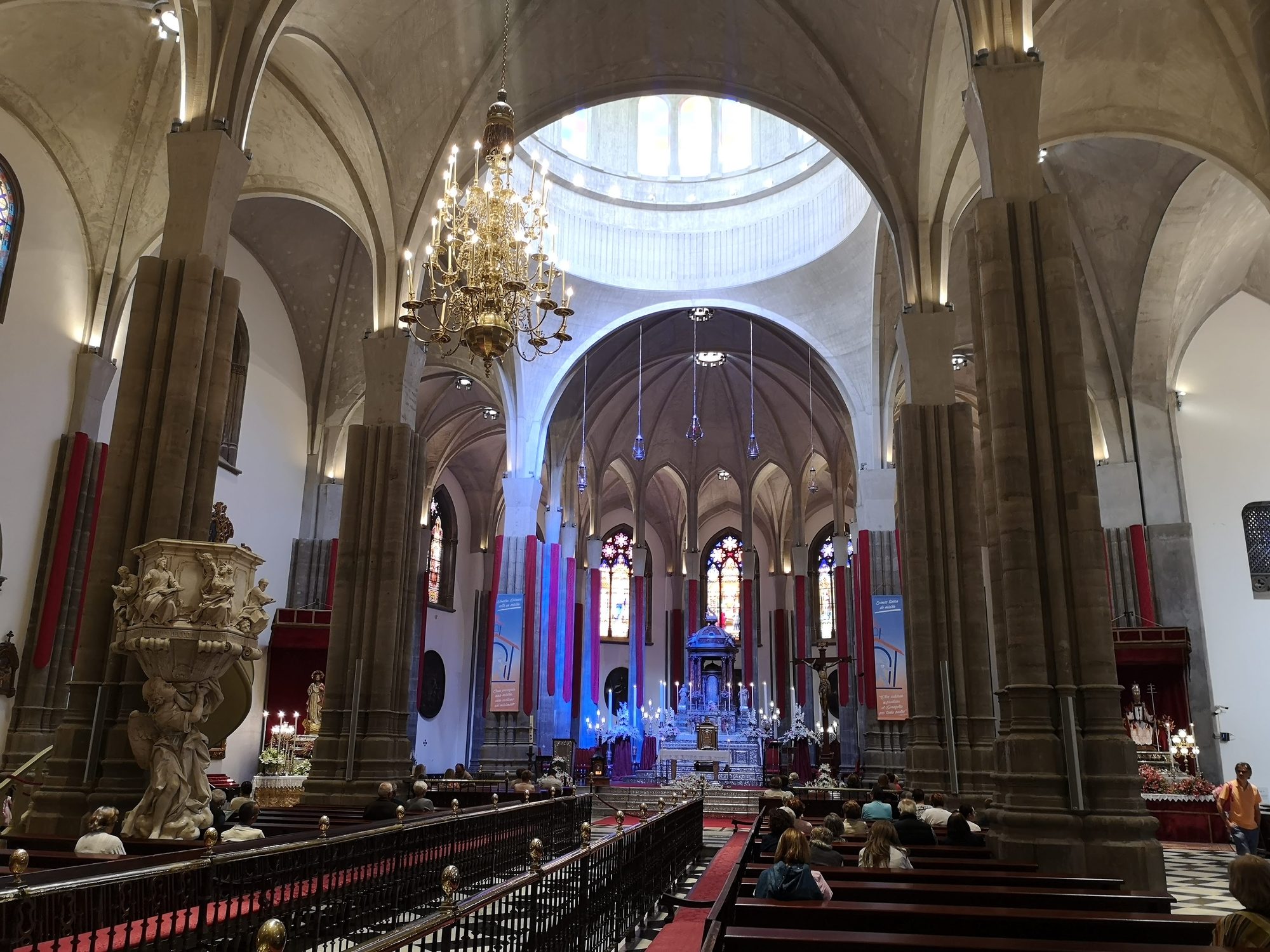 Interior de una catedral con altos arcos de piedra, cúpula luminosa y altar mayor.