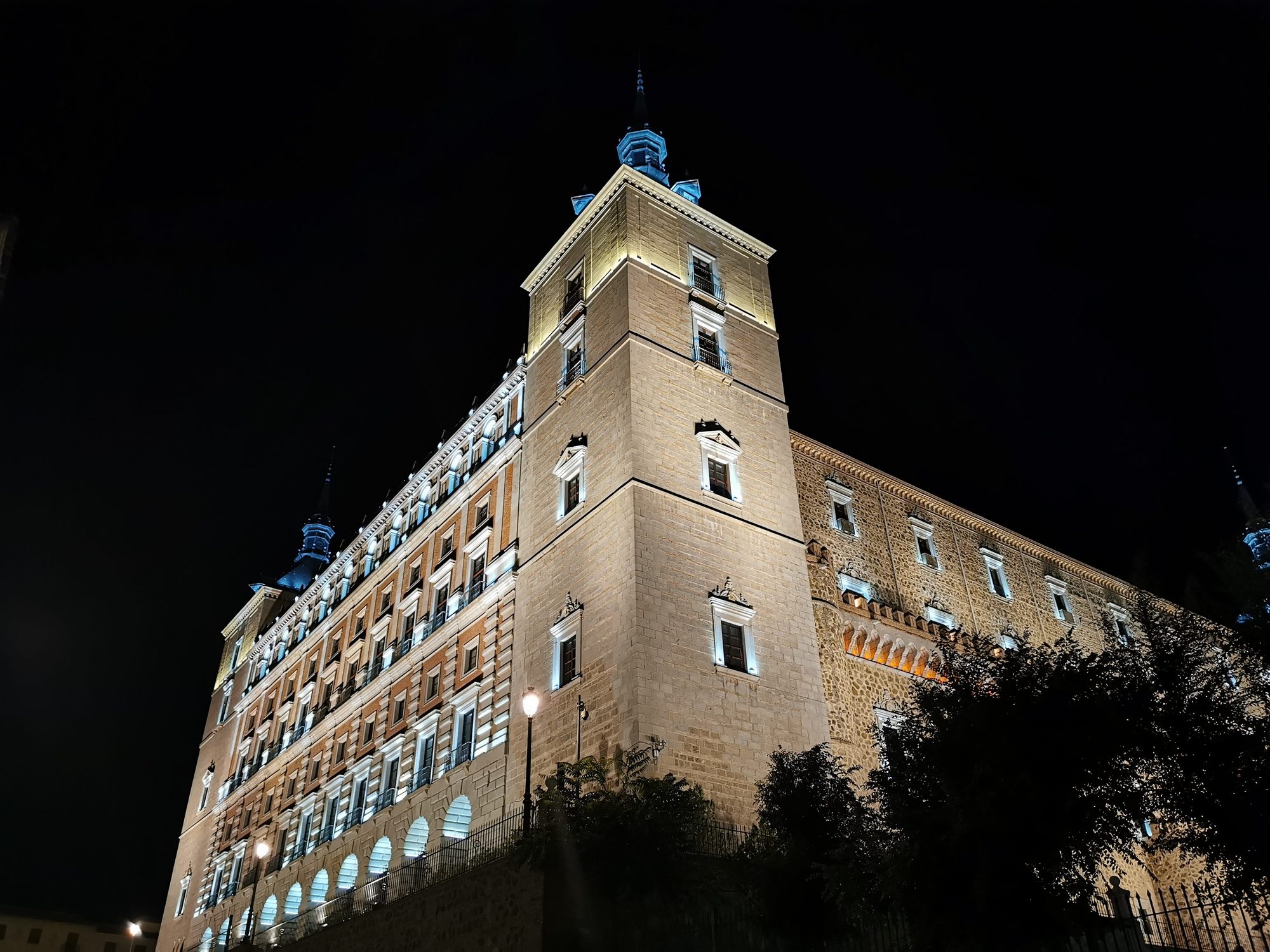 Fachada y torre iluminadas del Alcázar de Toledo bajo el cielo nocturno.