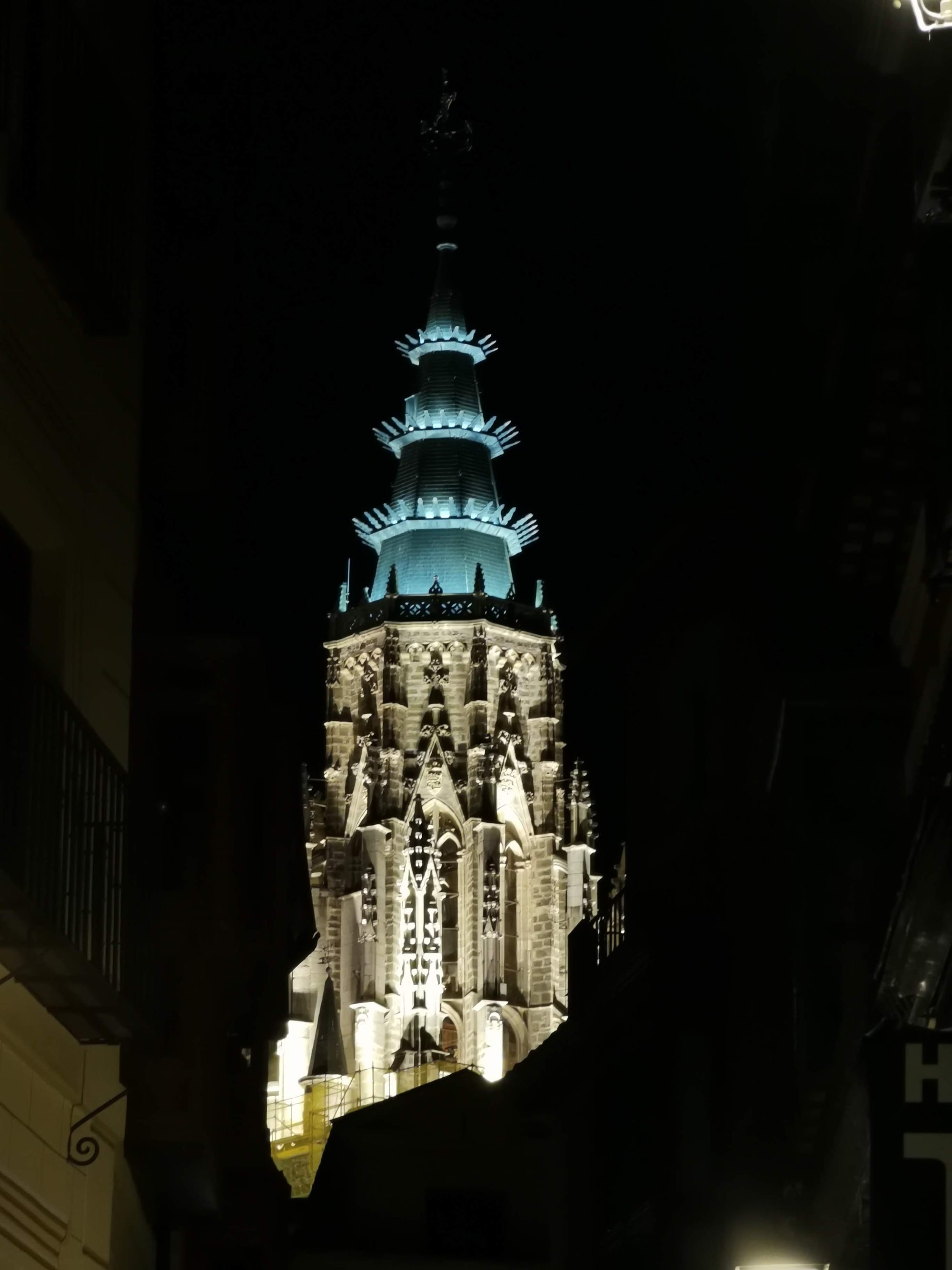 Torre gótica iluminada de la Catedral de Toledo destacando en la noche oscura.
