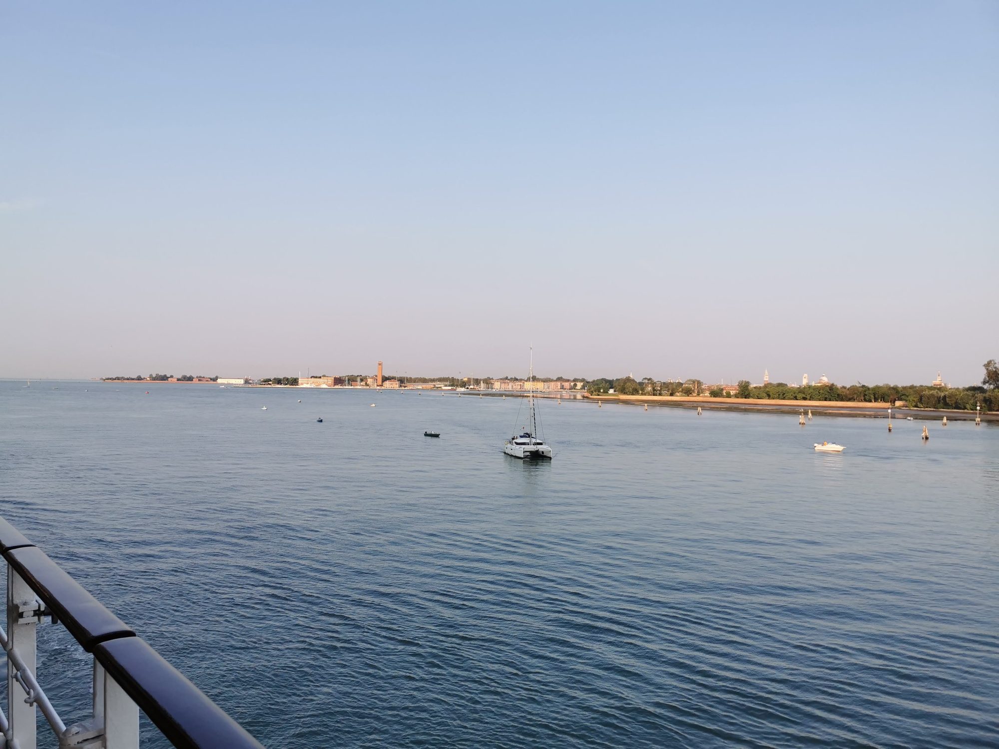 Barco navegando en la laguna de Venecia con la costa a lo lejos.