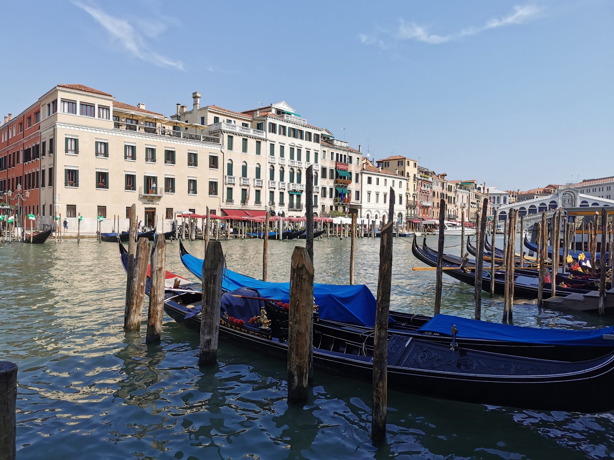 Góndolas amarradas en el Gran Canal de Venecia frente a edificios históricos tradicionales.