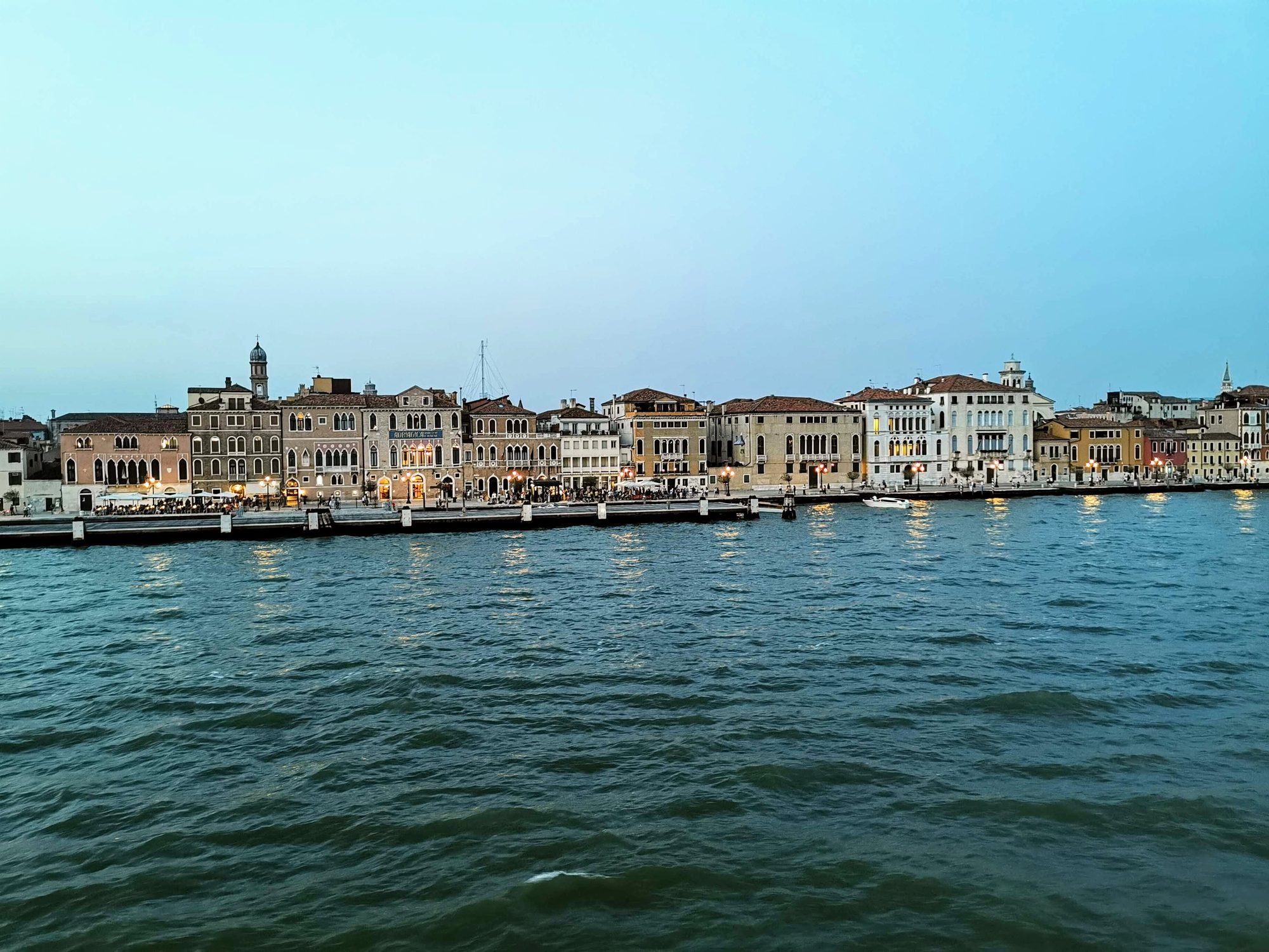 Paseo marítimo y edificios históricos de Venecia frente a la laguna al atardecer.