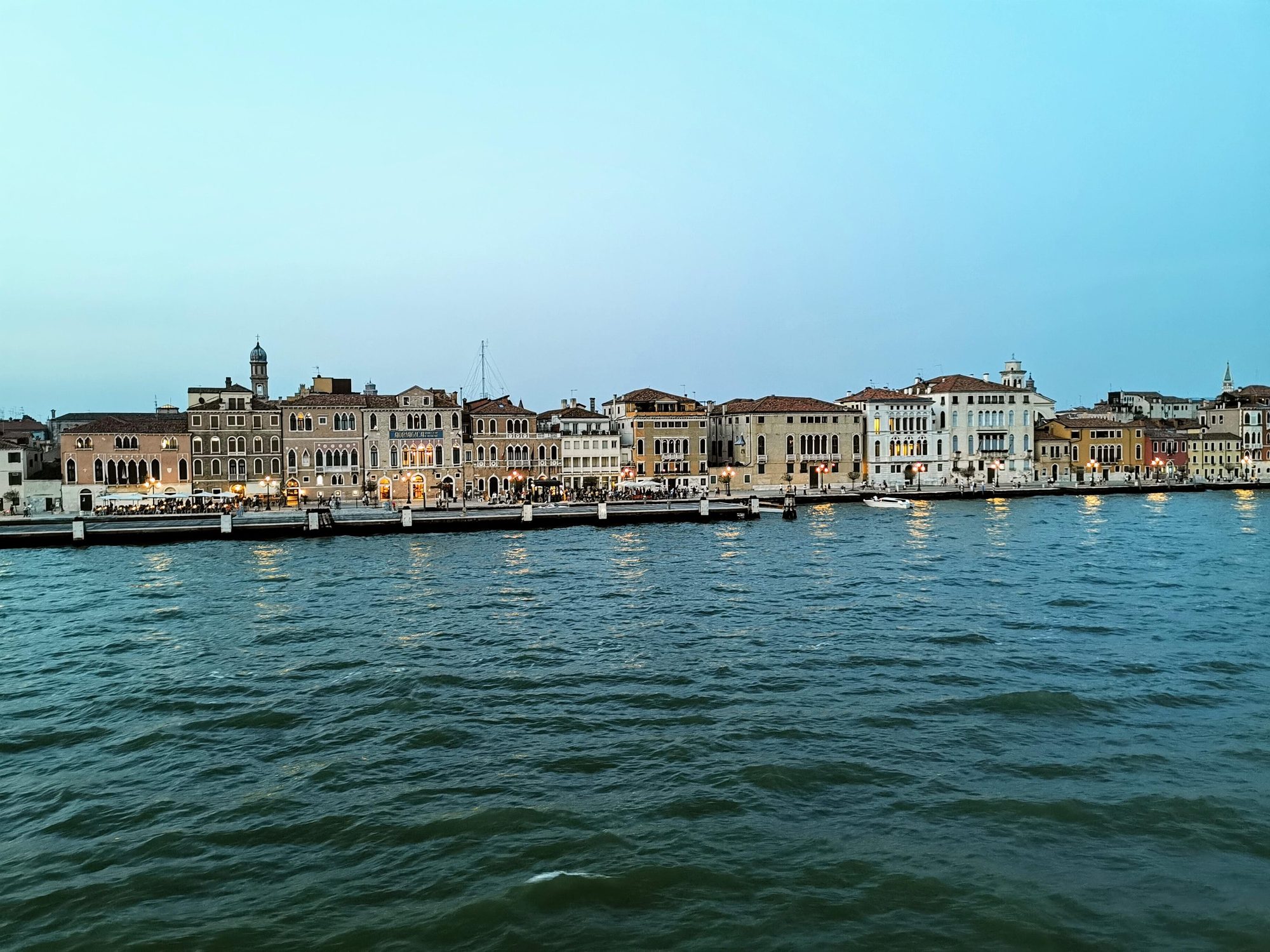 Edificios históricos iluminados junto al canal de Venecia durante el atardecer.