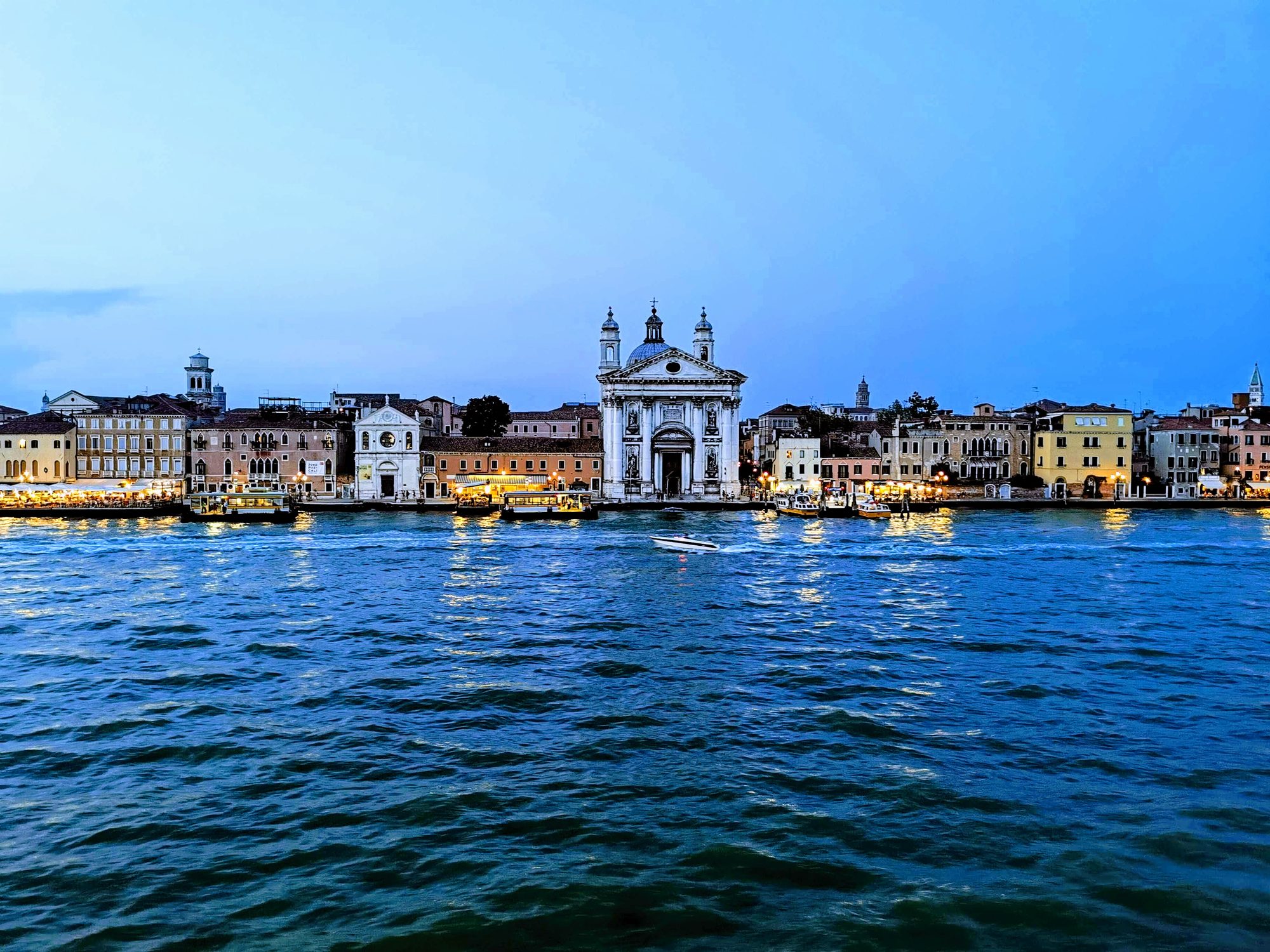 Canal de Venecia al anochecer con edificios históricos iluminados frente al agua.