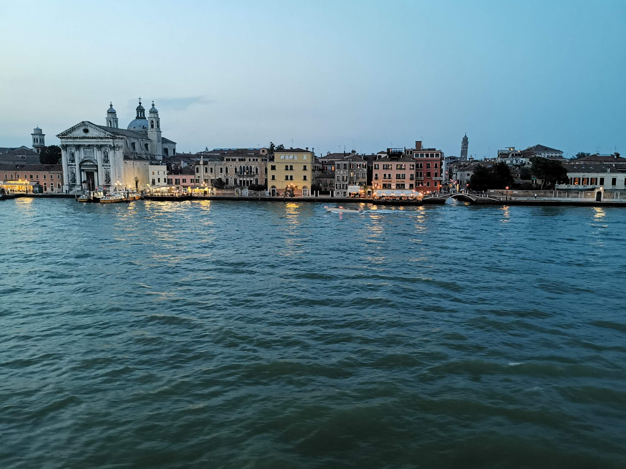Canal y edificios históricos iluminados al atardecer en el paseo marítimo de Venecia.
