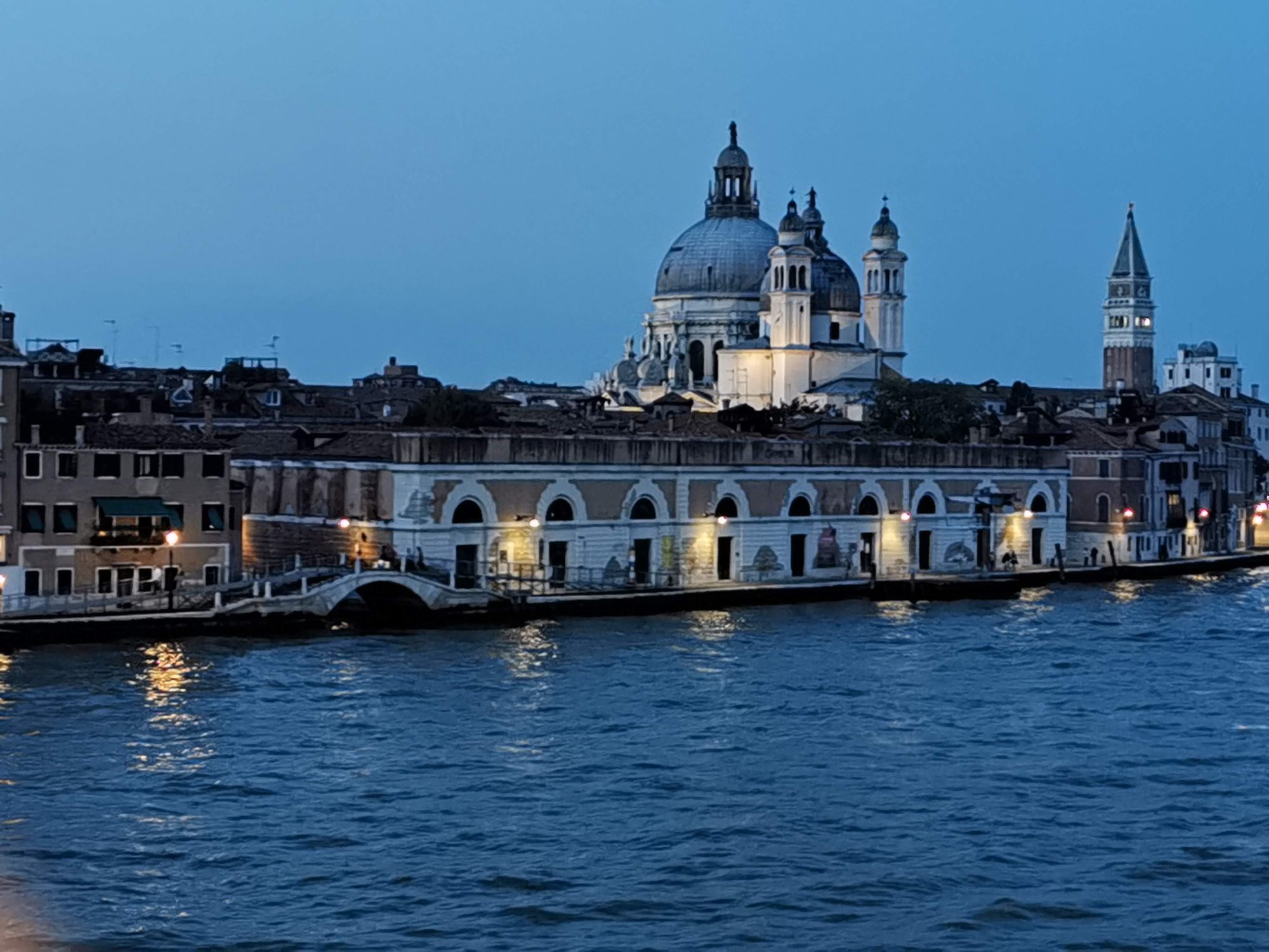 Basílica de Santa Maria della Salute iluminada al anochecer desde el agua en Venecia.