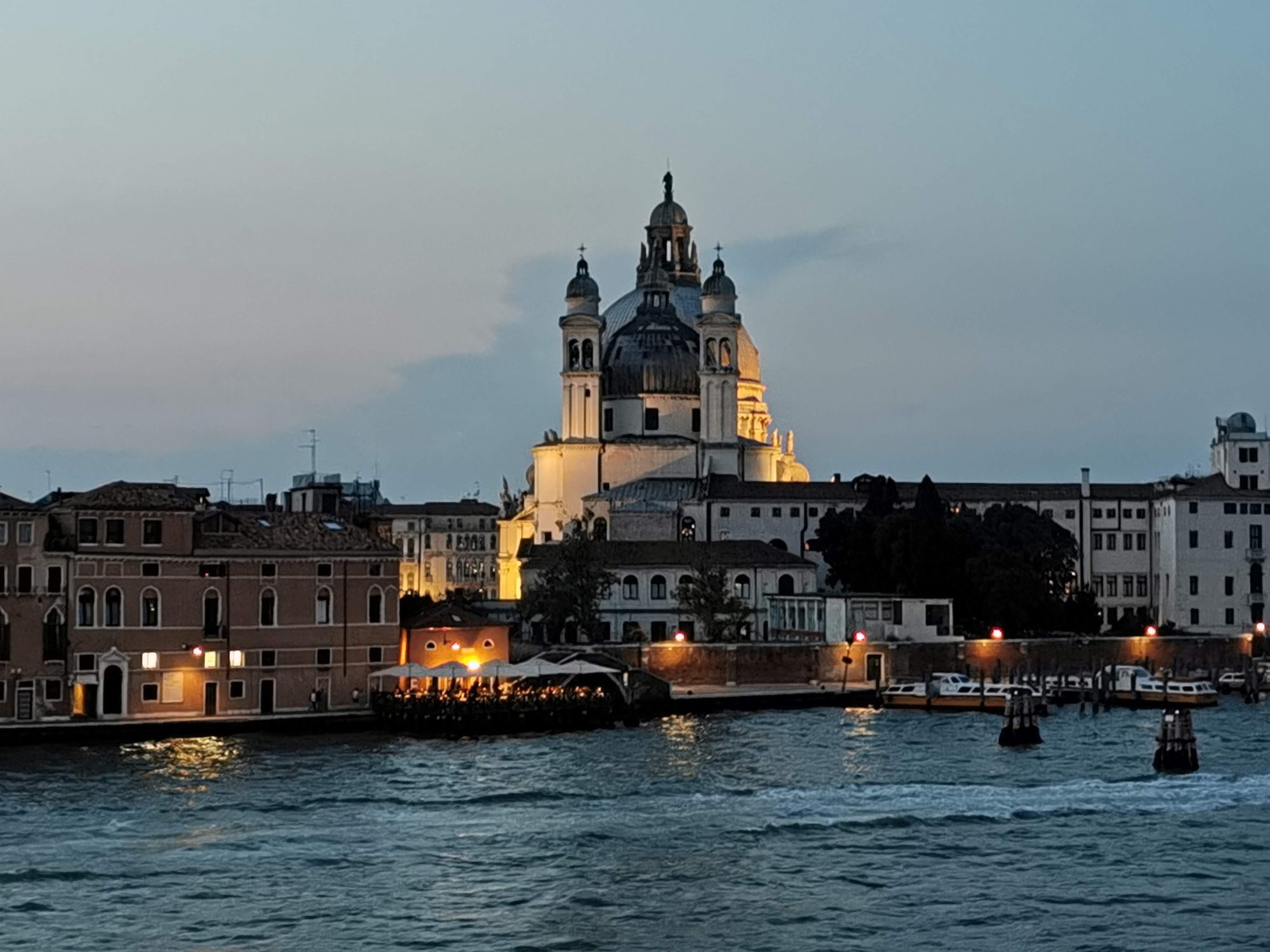 Basílica de Santa Maria della Salute iluminada al anochecer frente al agua en Venecia.