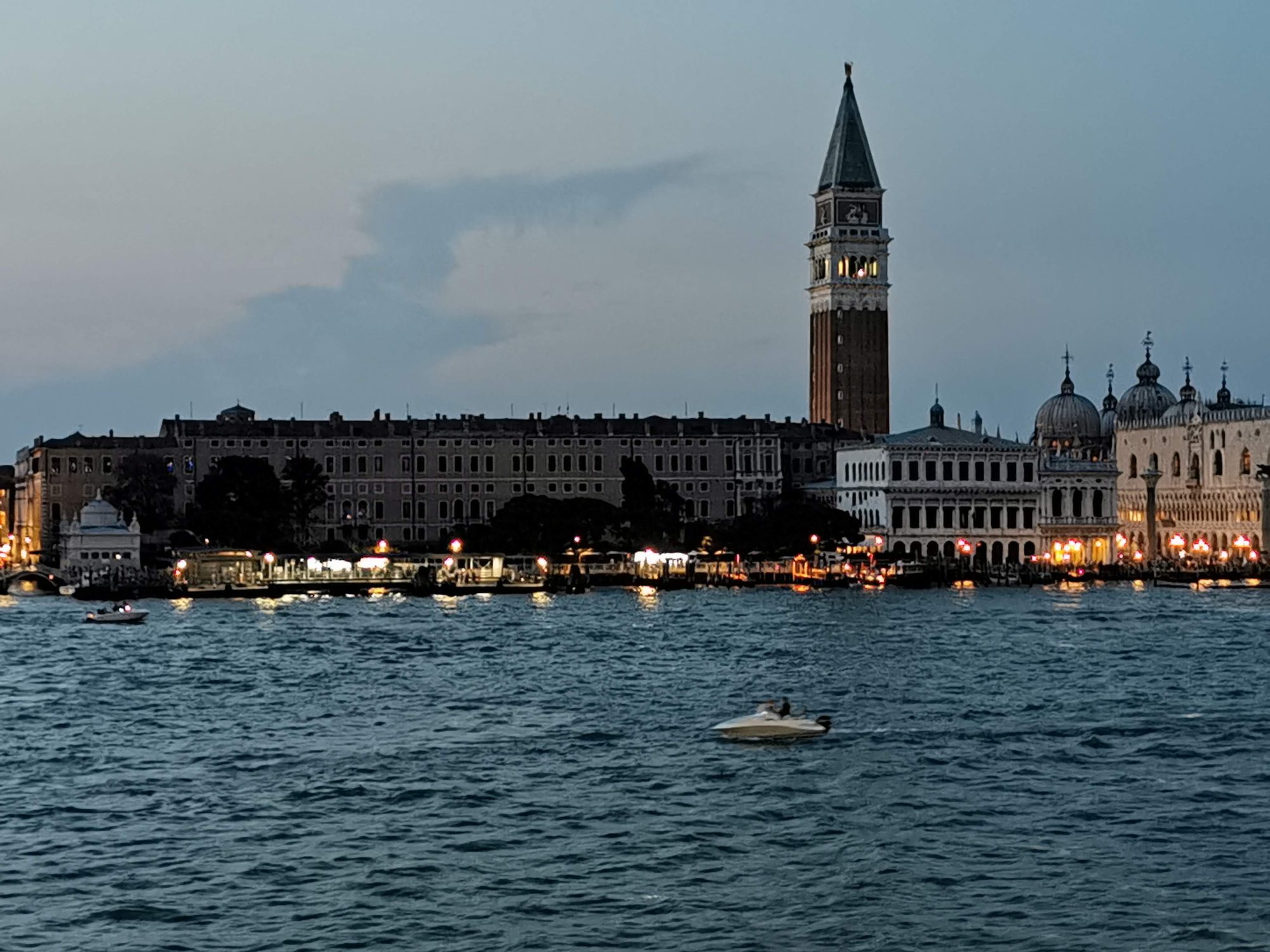Campanario de San Marcos y costa iluminada al atardecer sobre la laguna de Venecia.