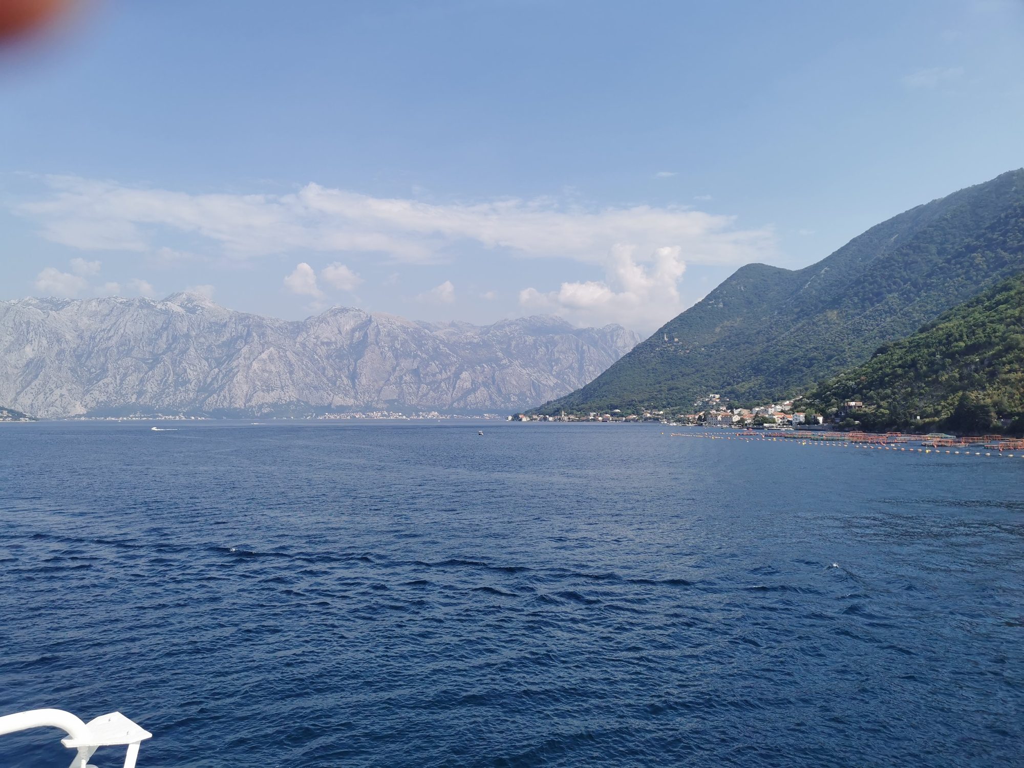 Aguas azules de la bahía de Kotor rodeadas de montañas bajo un cielo despejado.
