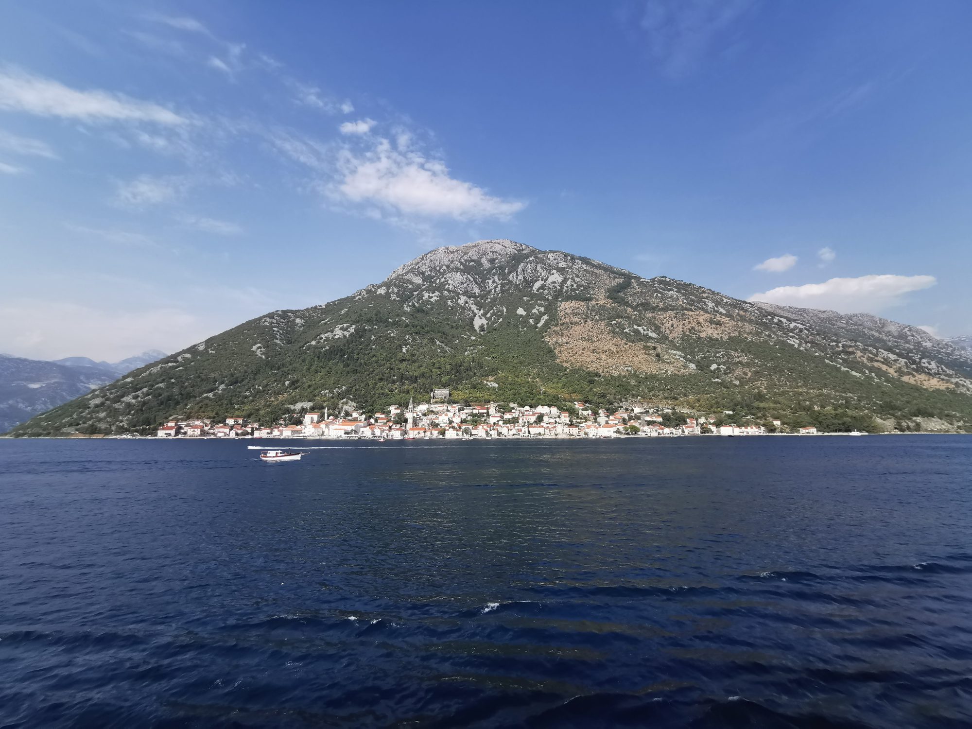 Vista panorámica del pueblo costero de Perast al pie de una gran montaña.