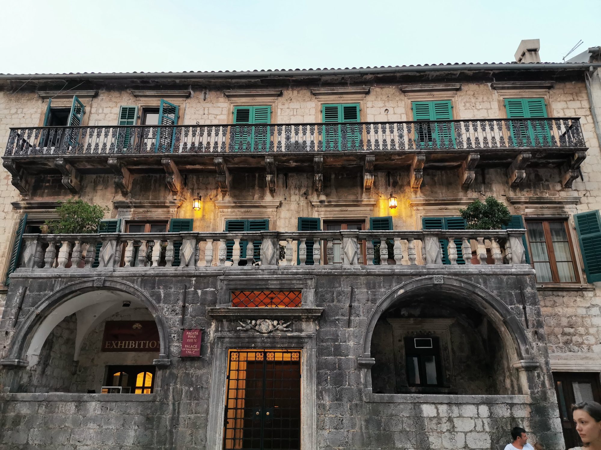 Fachada de piedra del Palacio Pima con balcones y contraventanas verdes en Kotor.
