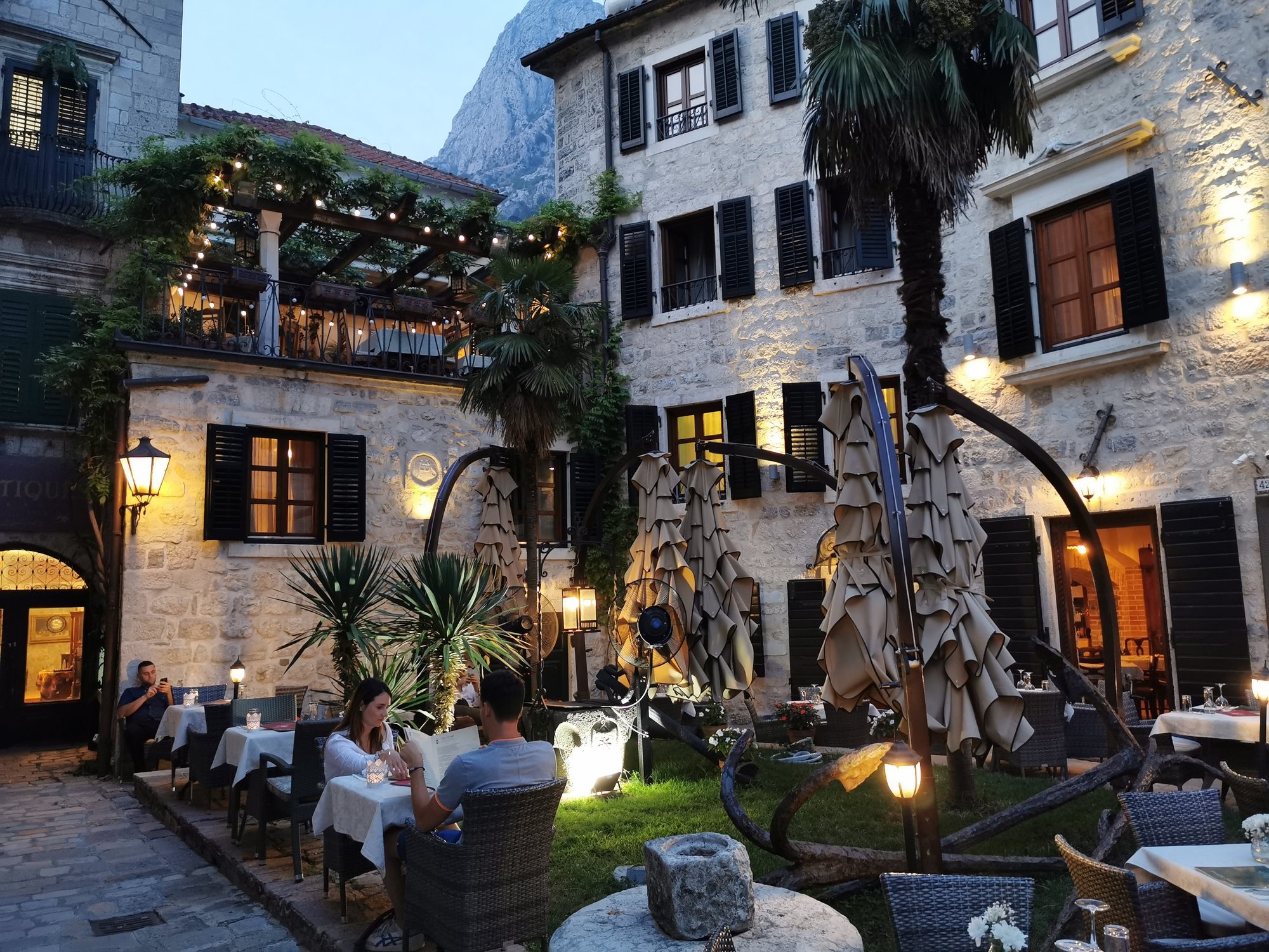 Terraza de restaurante iluminada en un patio de piedra tradicional al atardecer.