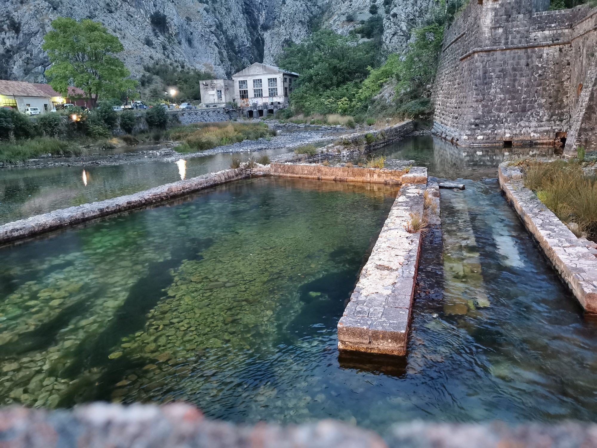 Canales de agua cristalina junto a las antiguas murallas de piedra en Kotor.