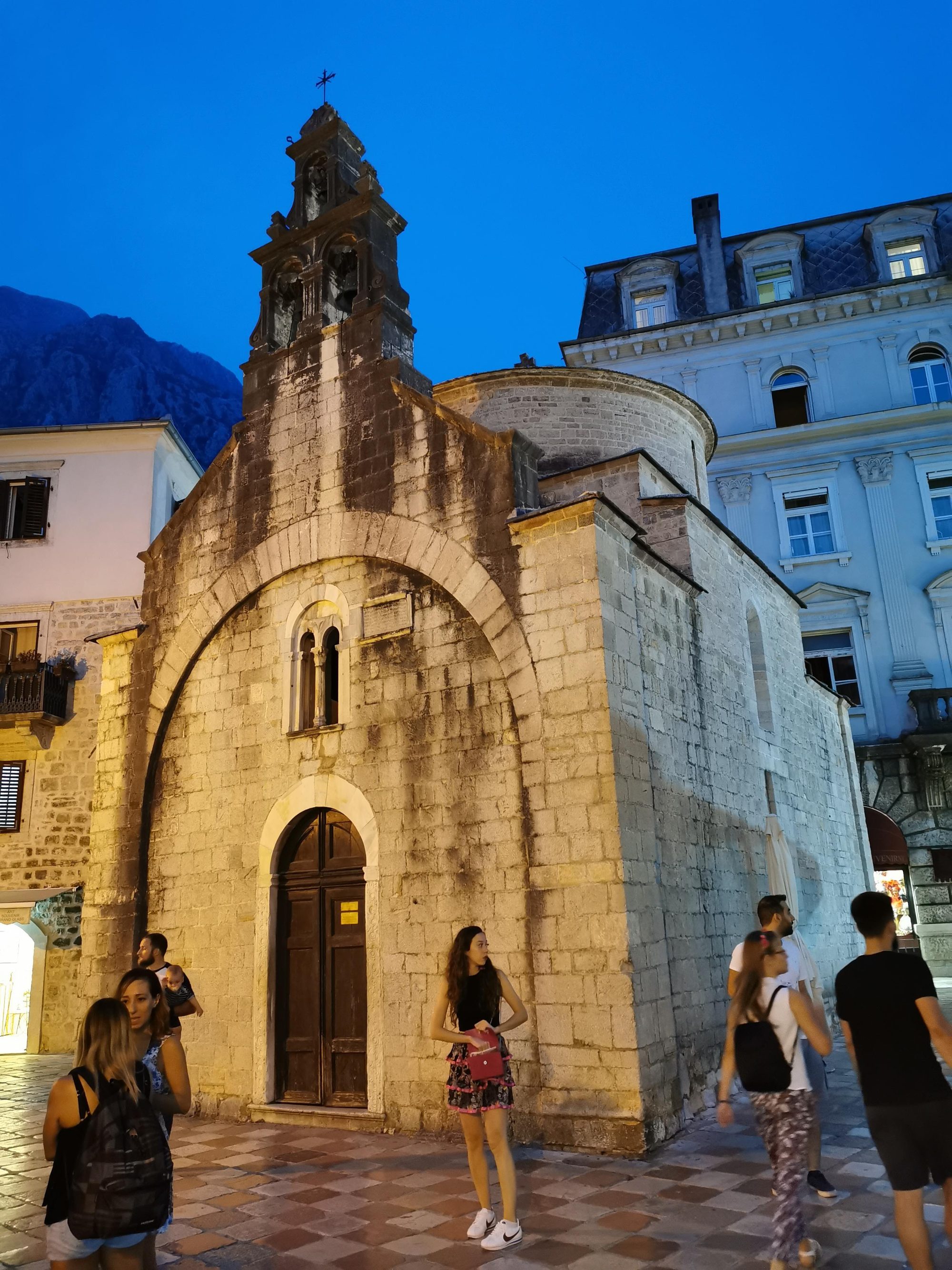 Iglesia medieval de San Lucas iluminada al anochecer en una plaza de Kotor.