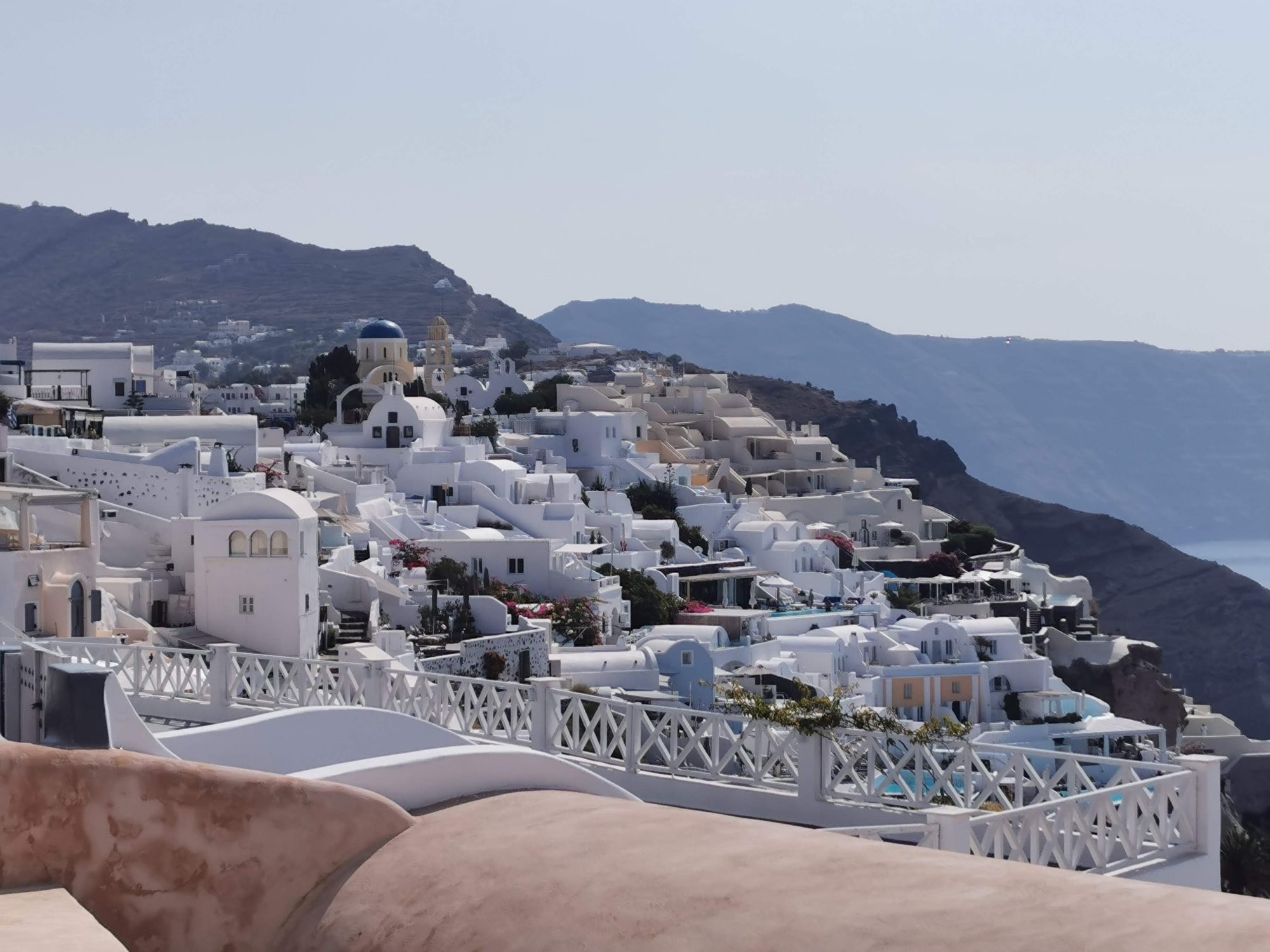 Casas blancas tradicionales y cúpulas azules en la ladera de Oia, Santorini.