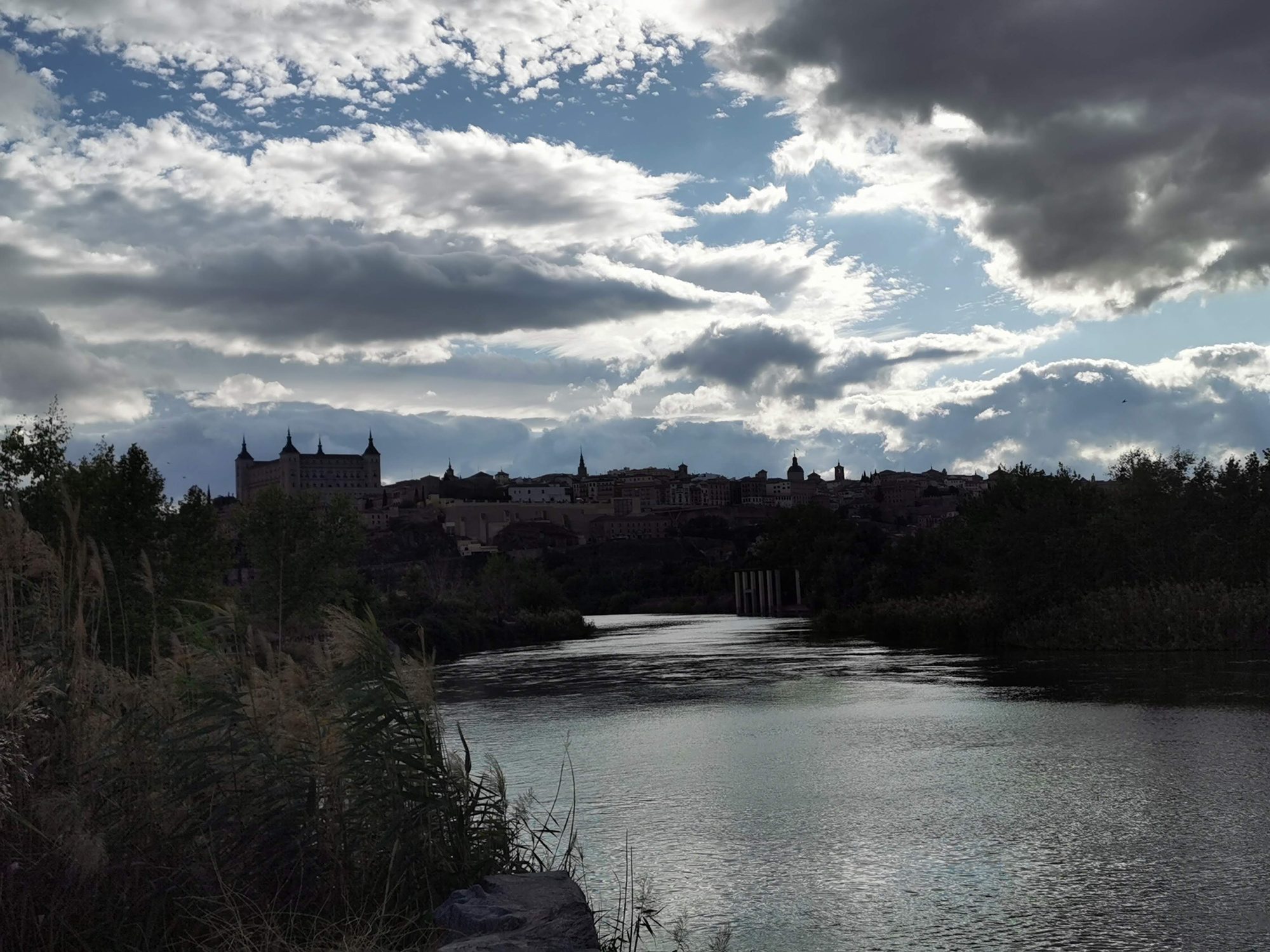 Panorámica de Toledo y el Alcázar sobre el río Tajo bajo un cielo nublado.