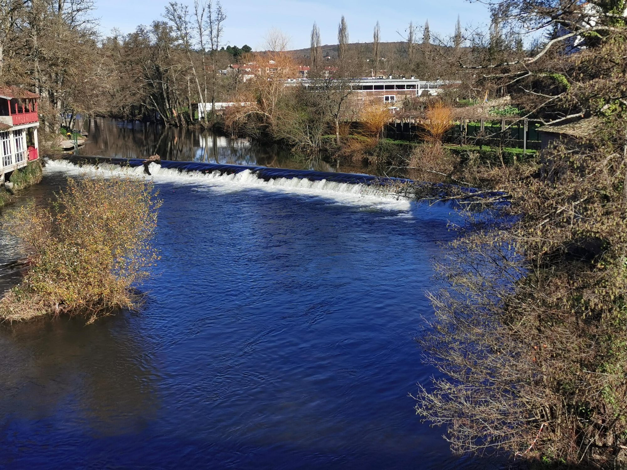 Presa y aguas azules del río Arnoia rodeadas de vegetación invernal en Allariz.