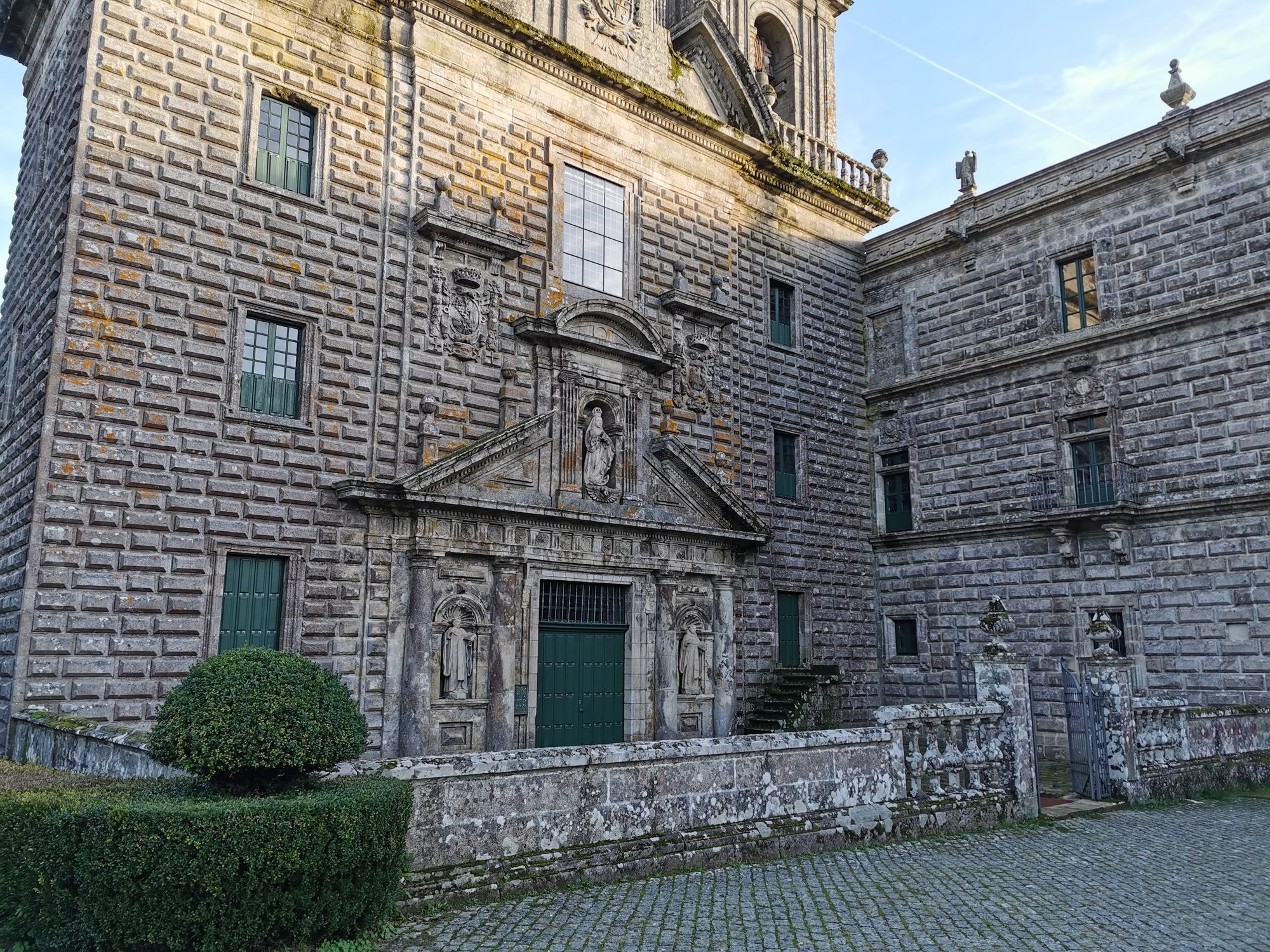 Fachada de piedra almohadillada del Monasterio de Oseira con esculturas y detalles barrocos.
