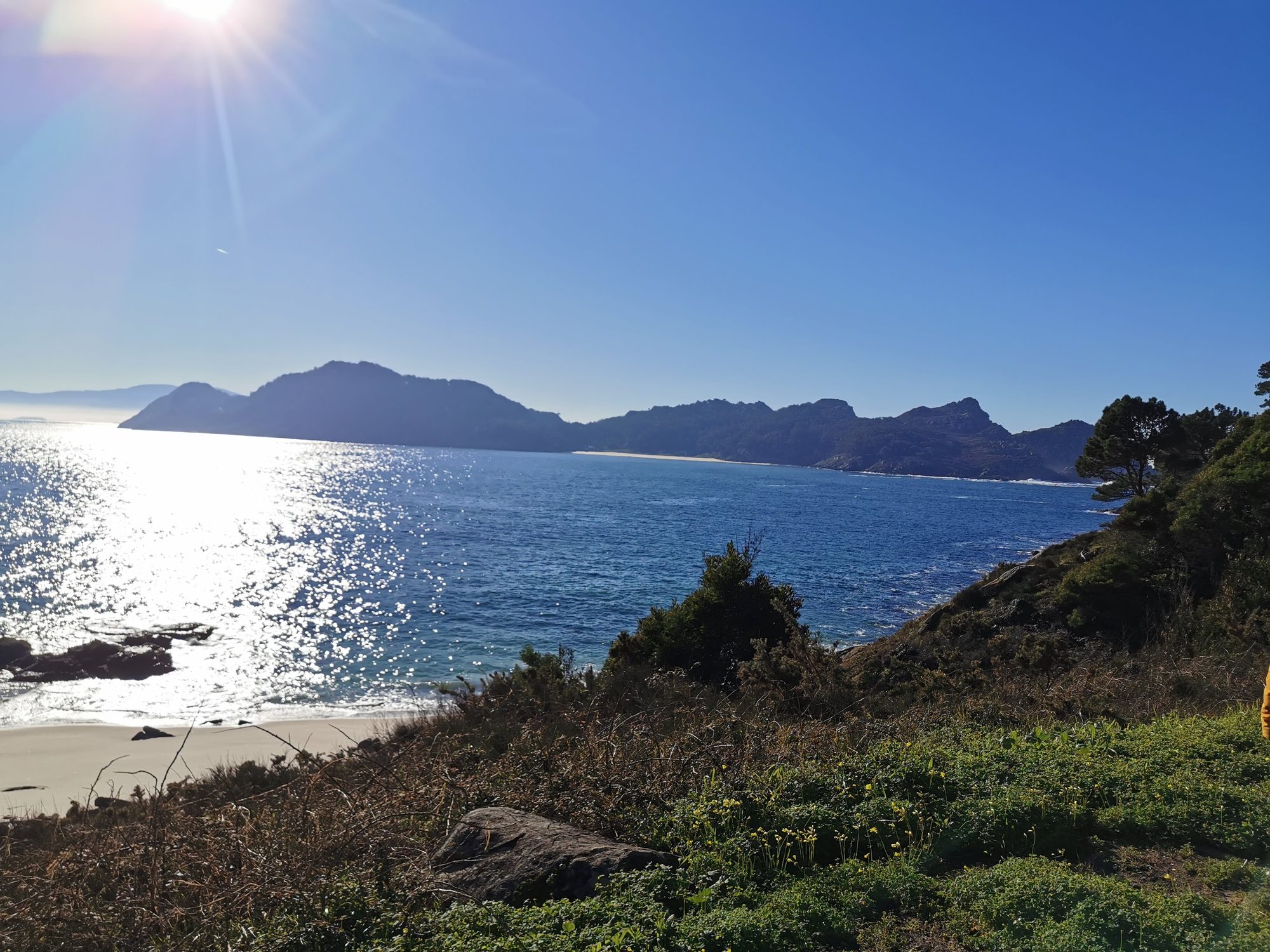 Vista panorámica del mar brillante y las islas montañosas bajo un sol radiante.