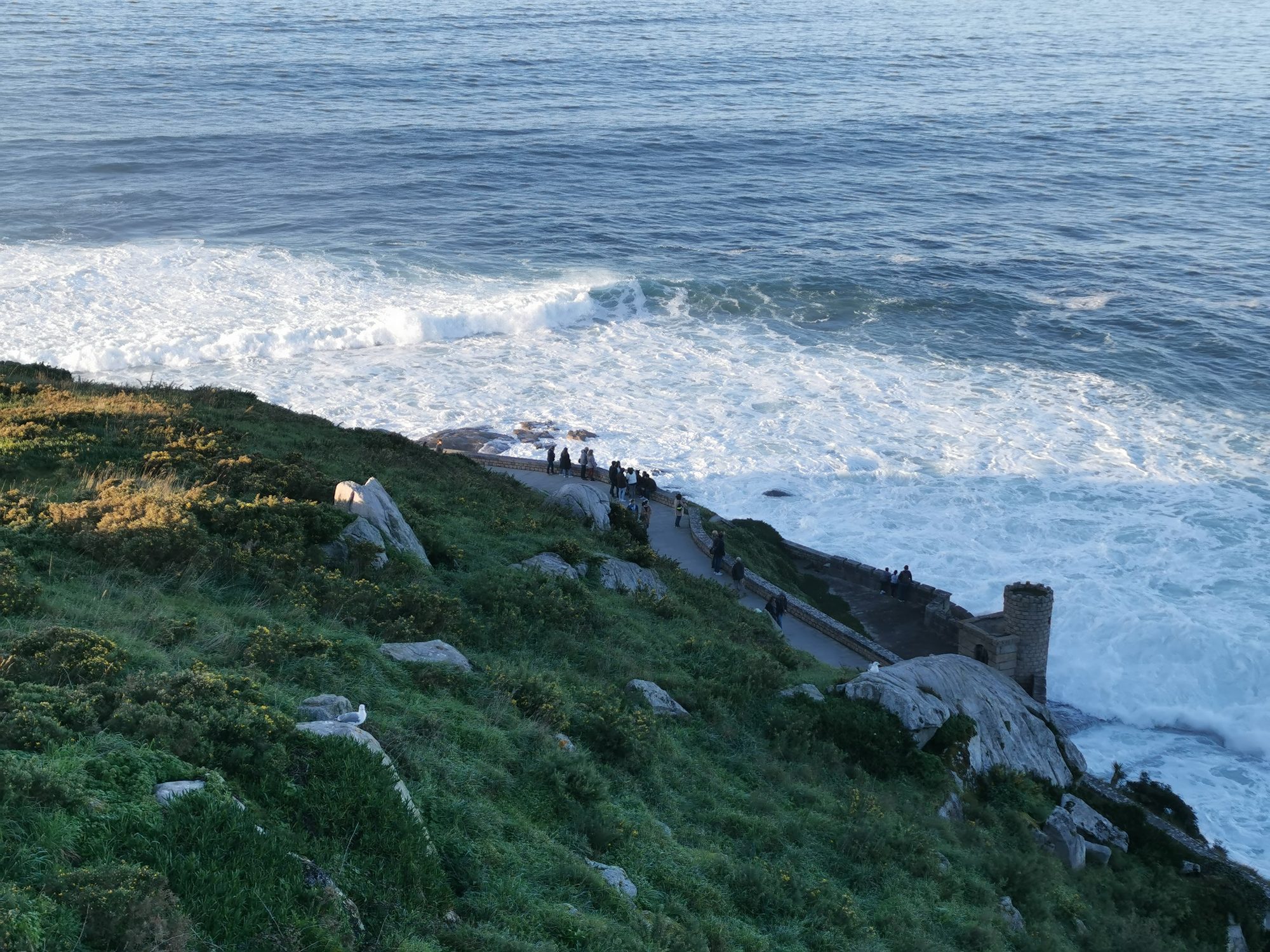 Paseo marítimo y murallas de piedra junto a las olas del mar en Baiona.