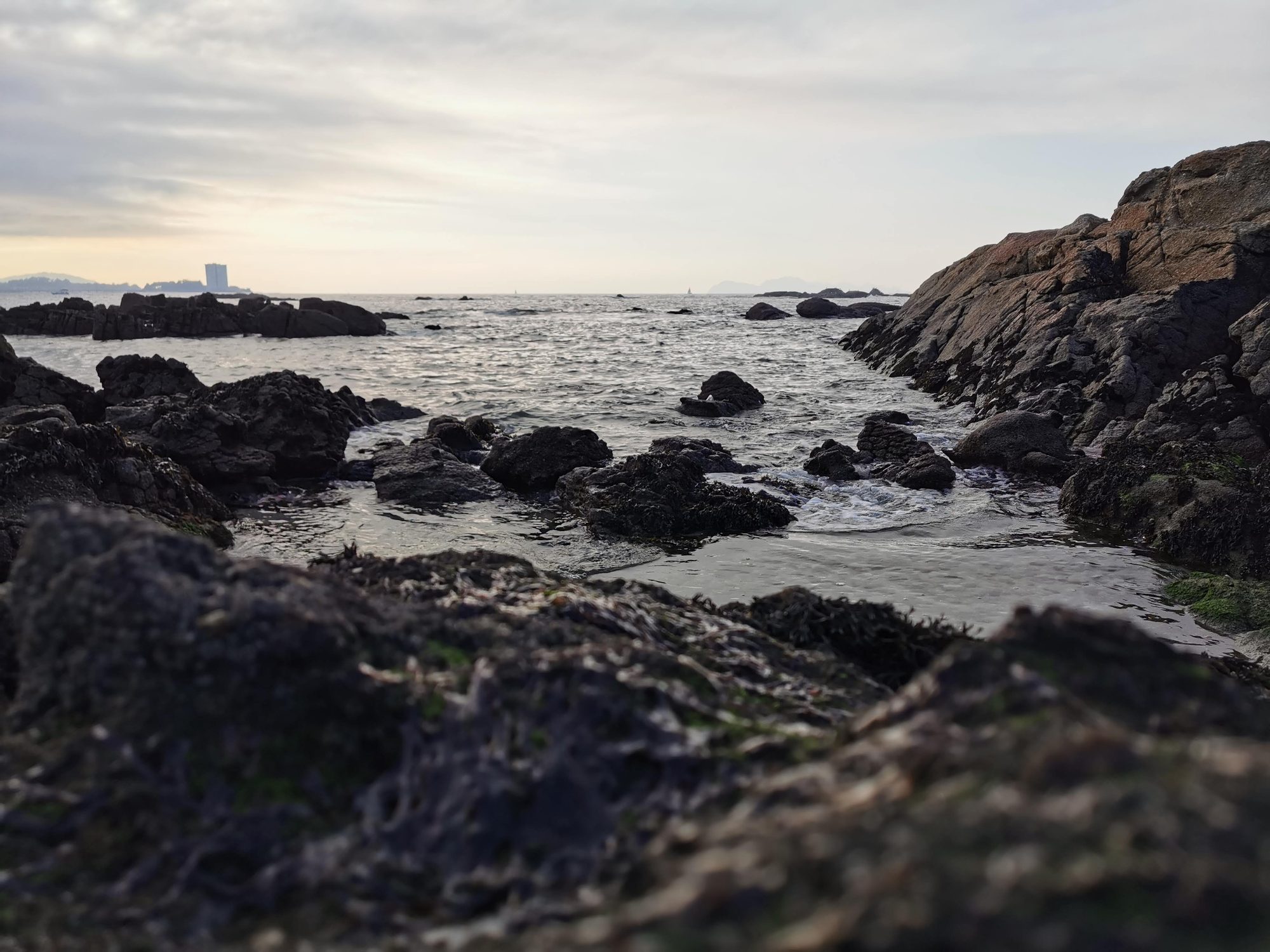 Formaciones rocosas en la orilla del mar bajo un cielo nublado al atardecer.