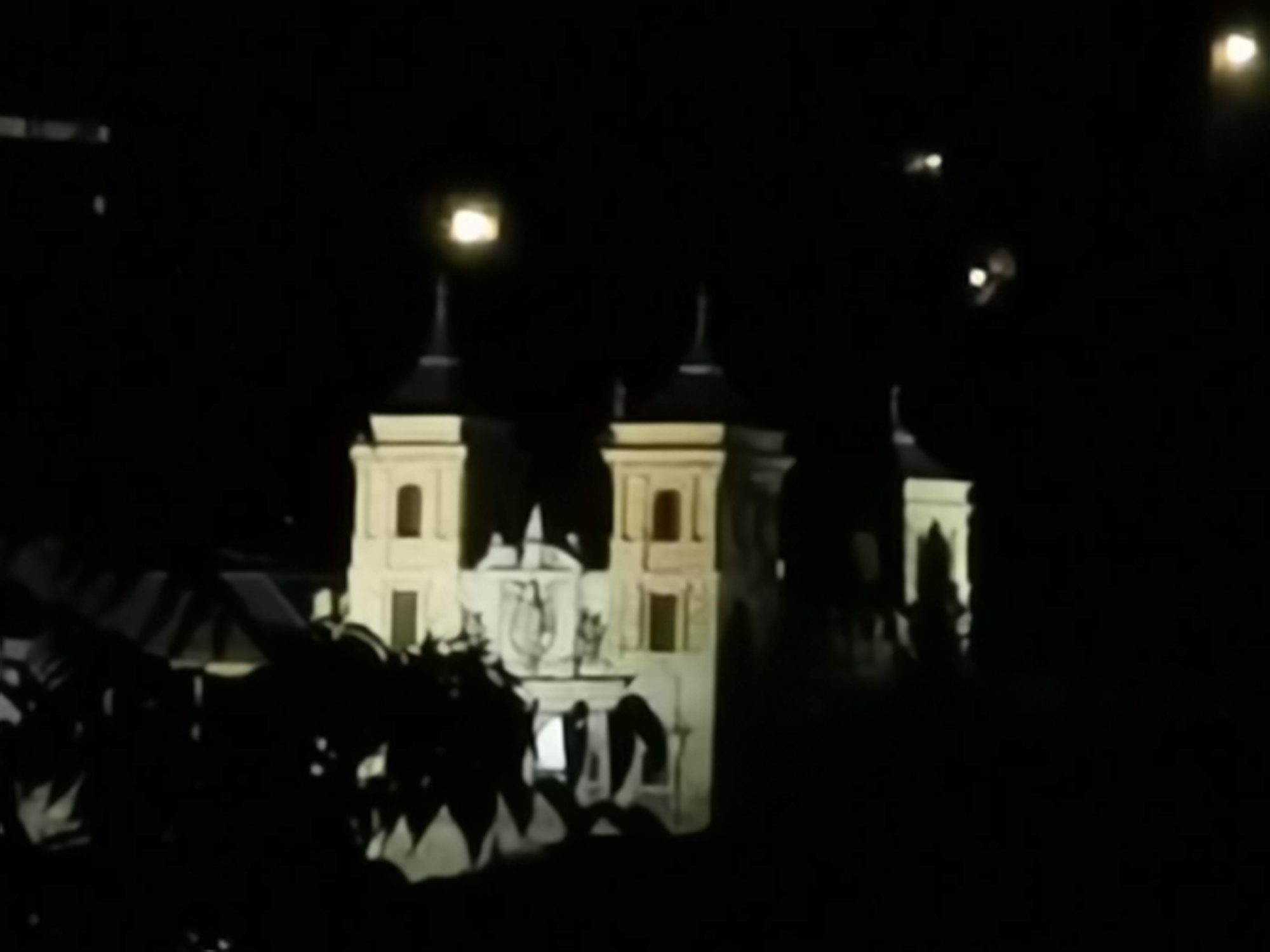 Fachada y torres de una iglesia barroca iluminada de noche en Toledo.