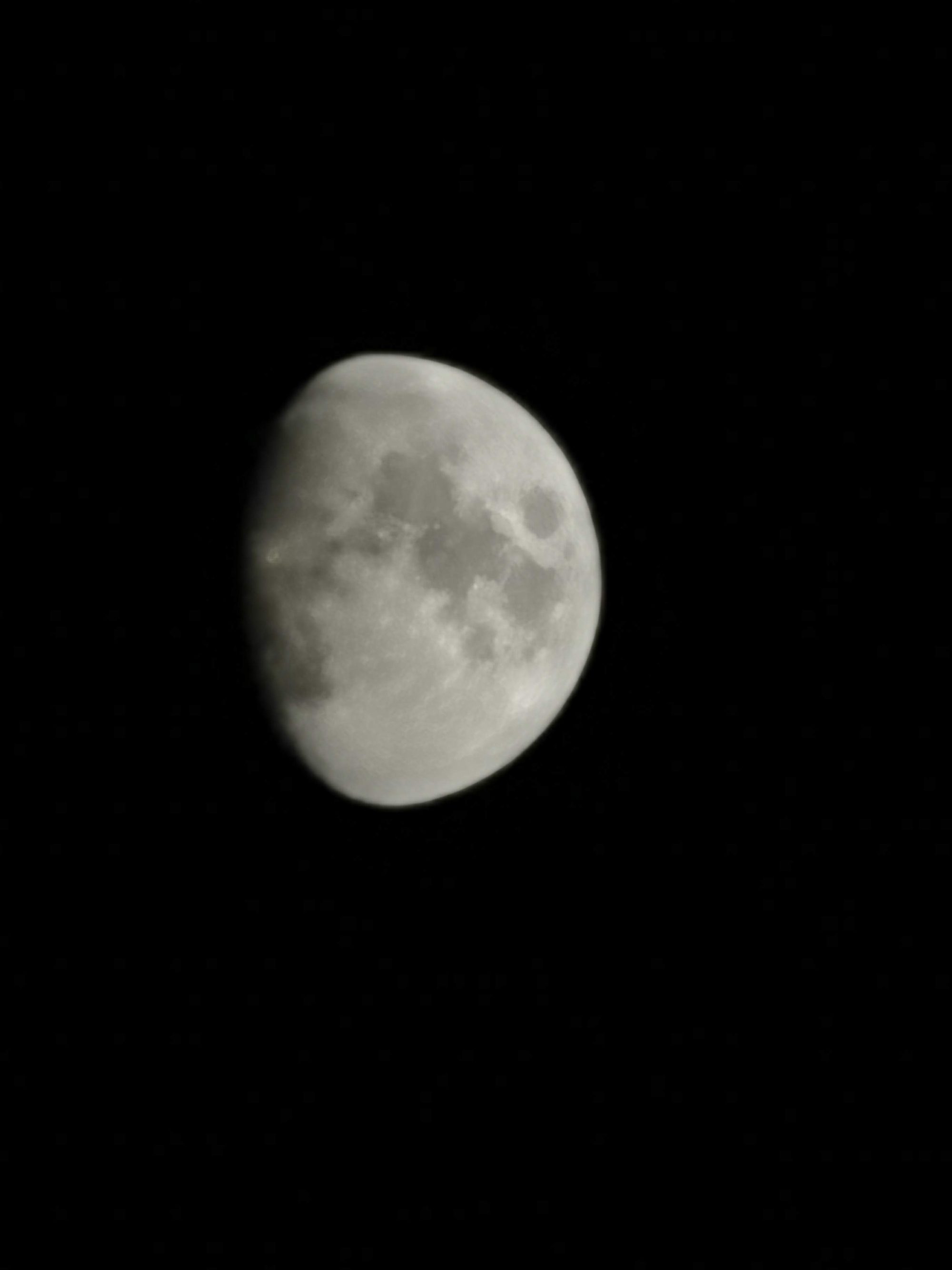 Luna gibosa iluminada sobre el fondo negro de la noche despejada.