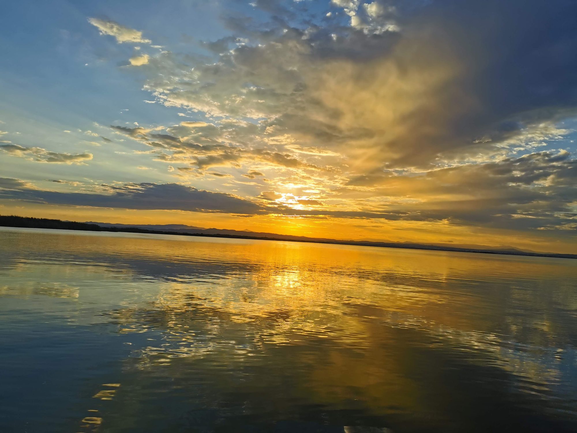 Atardecer dorado reflejado sobre las aguas tranquilas de la Albufera en Valencia.