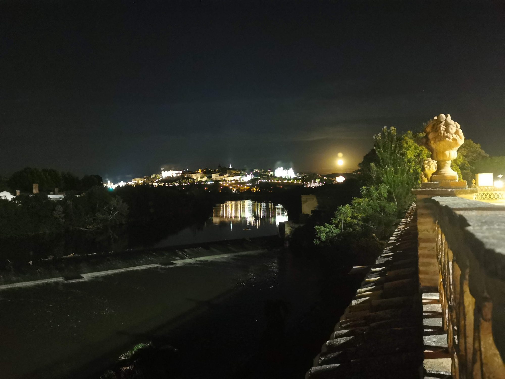 Vista nocturna de Toledo iluminada sobre el río Tajo bajo la luna.