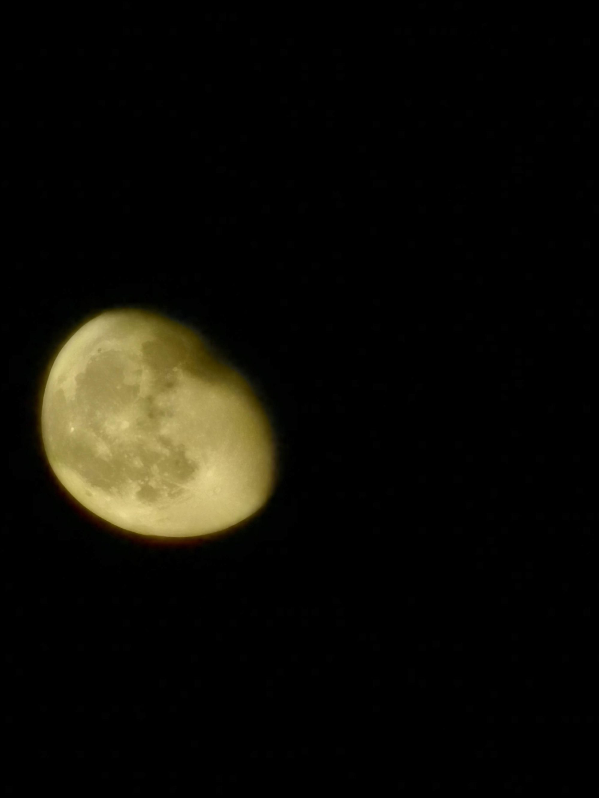 Luna gibosa iluminada con tonalidad dorada sobre un cielo nocturno completamente oscuro.