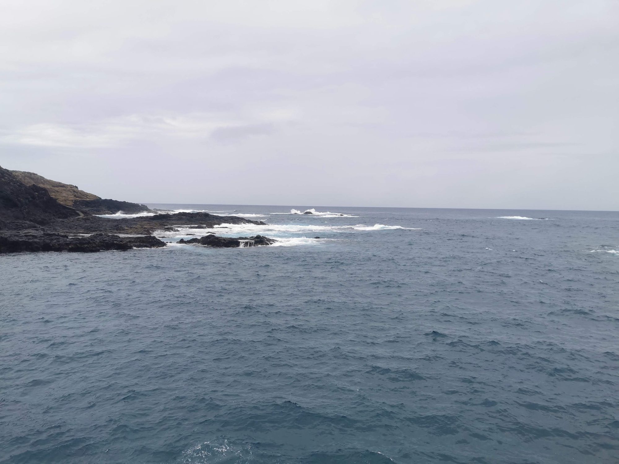 Costa volcánica rocosa con olas del océano Atlántico bajo un cielo nublado.