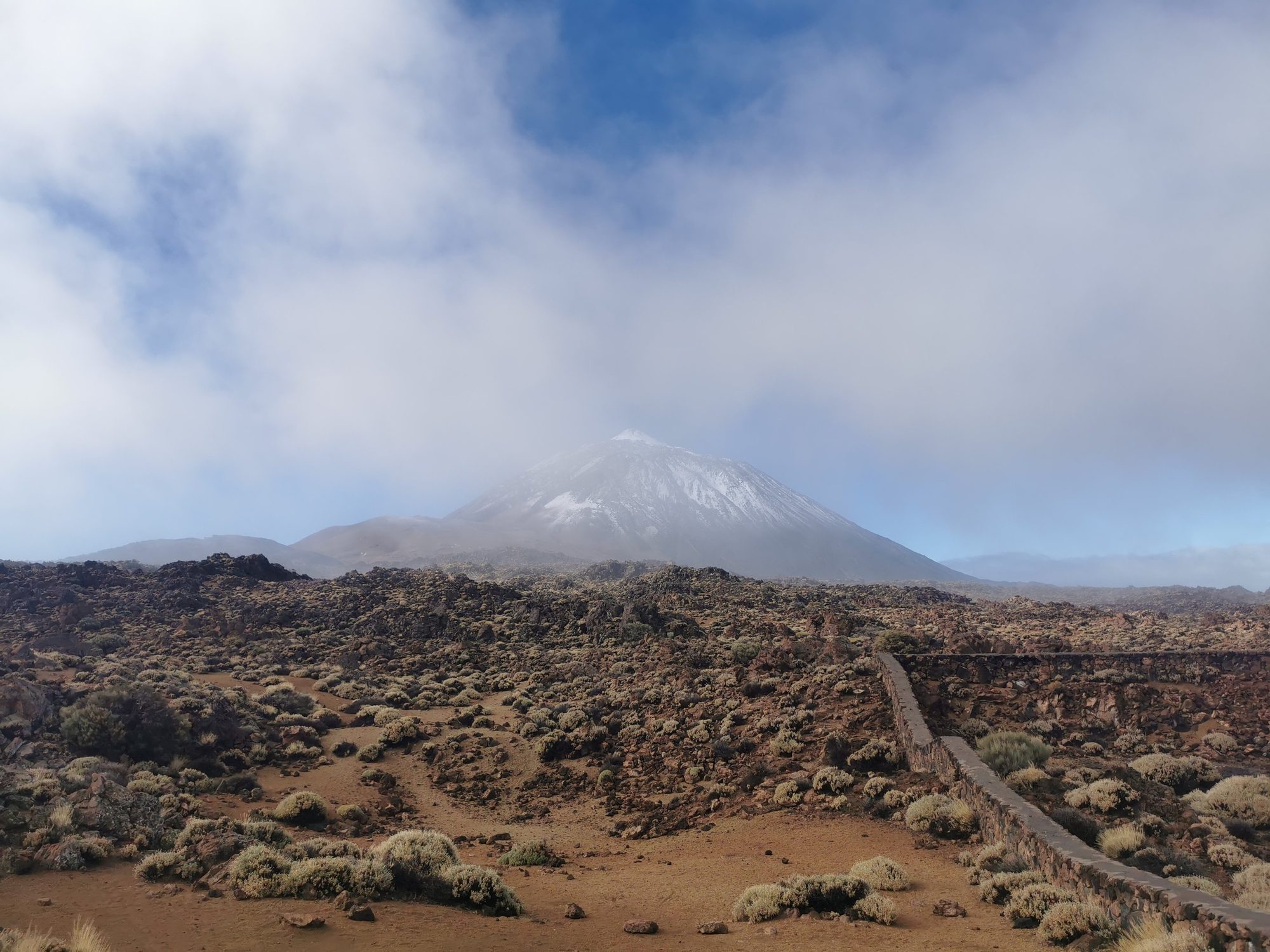 Pico del Teide nevado entre nubes sobre el paisaje volcánico de La Orotava.