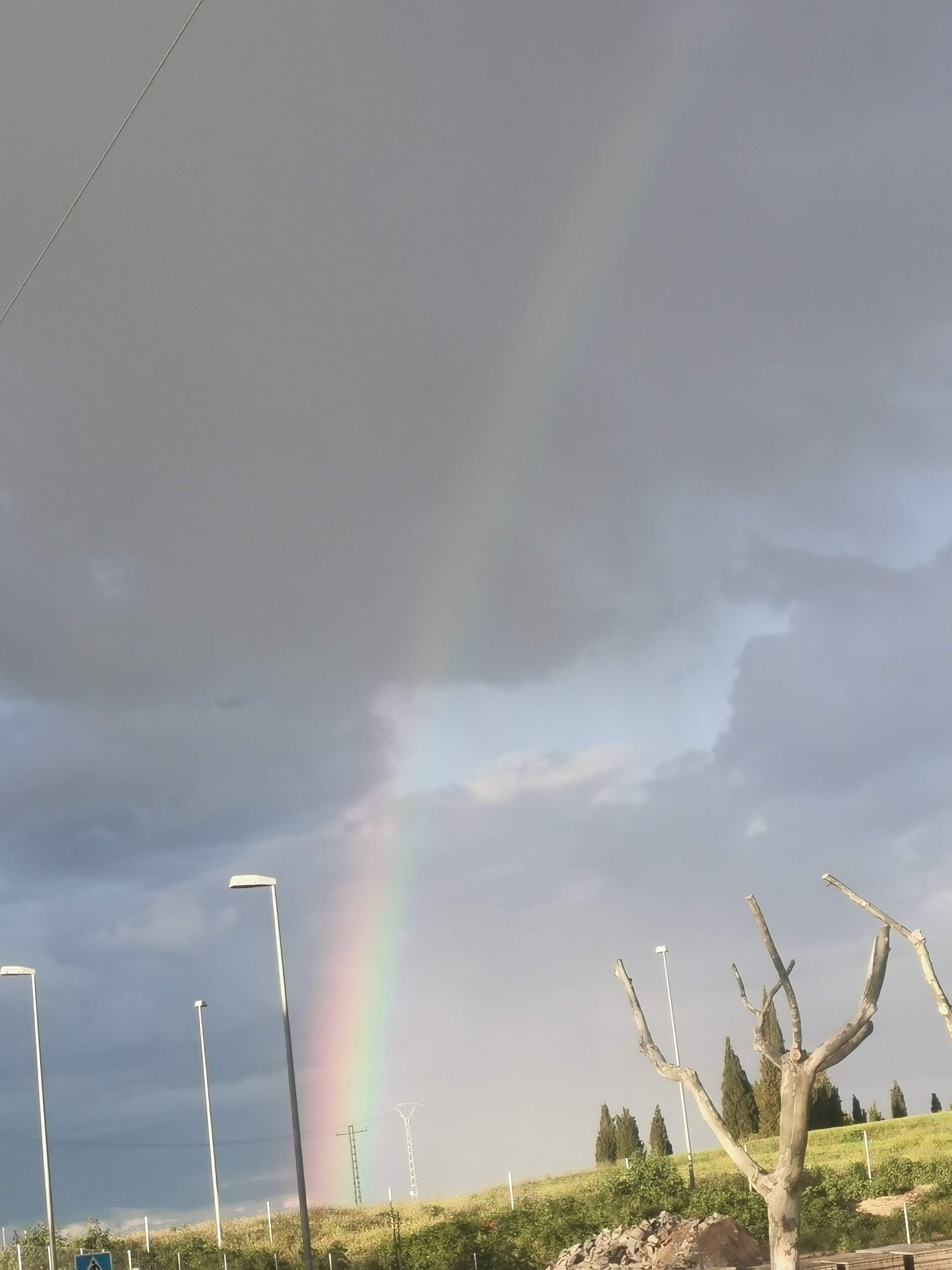 Arcoíris tenue bajo un cielo nublado y tormentoso sobre el campo de Bargas.