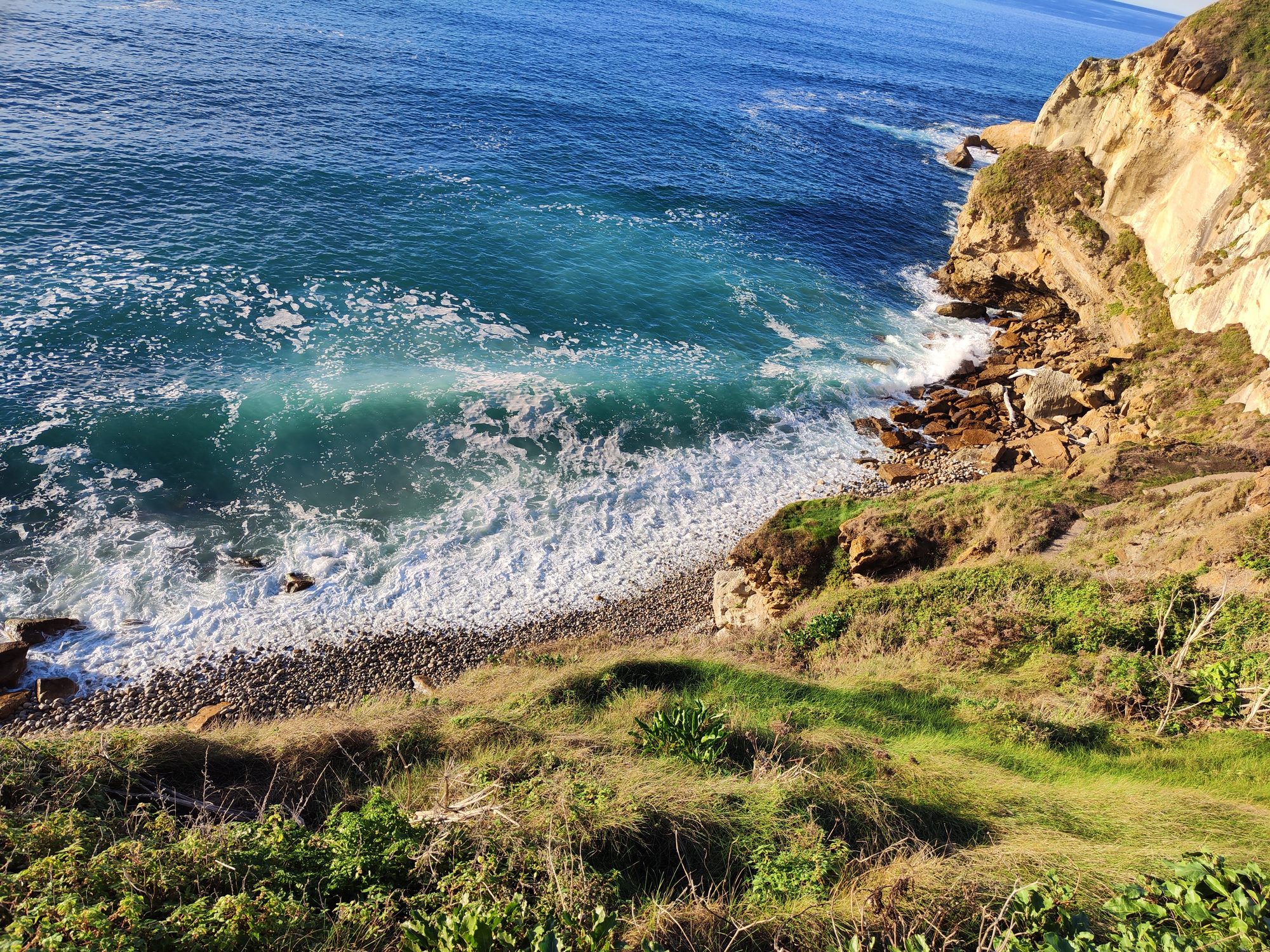 Acantilados verdes y olas del mar rompiendo en la costa rocosa de Suances.