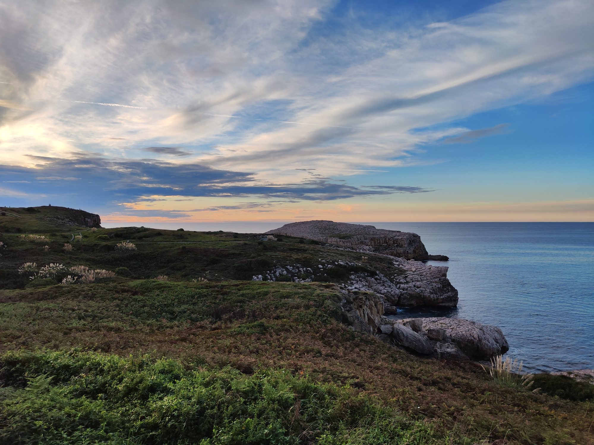Acantilados rocosos y praderas verdes frente al mar Cantábrico al atardecer en Suances.