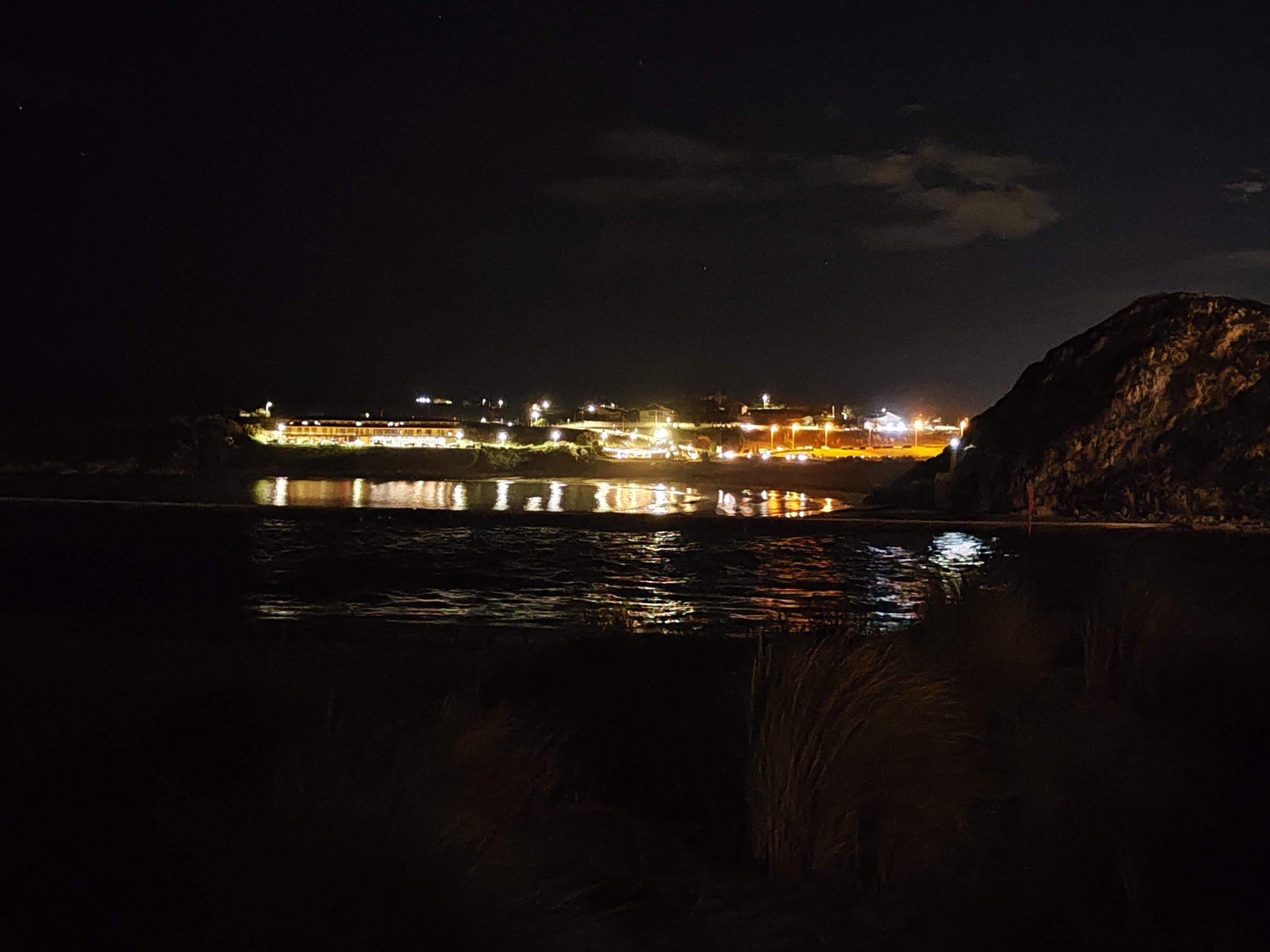 Luces nocturnas de la costa reflejadas en el agua tranquila del mar en Suances.