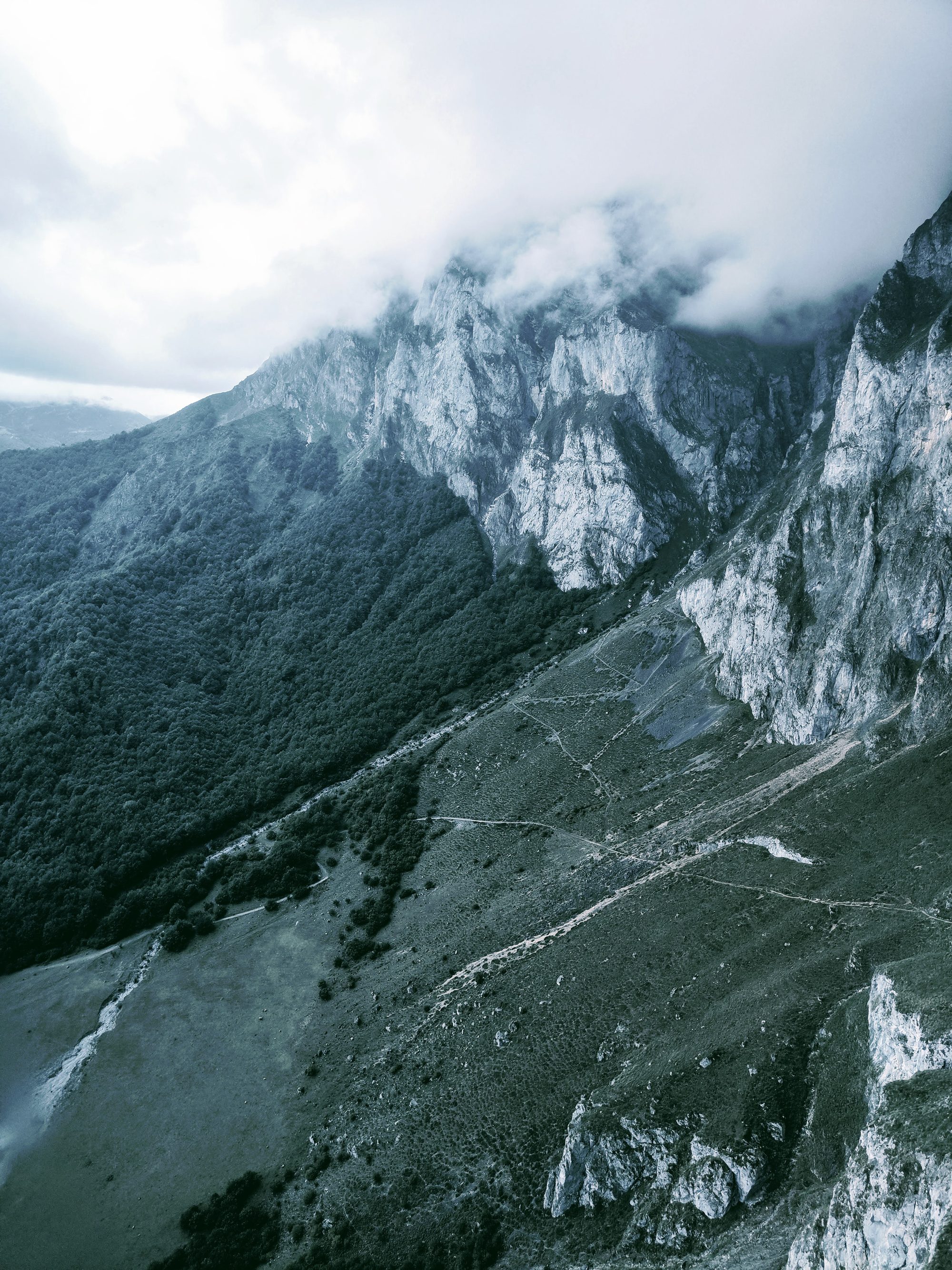Montañas escarpadas y laderas verdes envueltas por densas nubes y niebla en Camaleño.