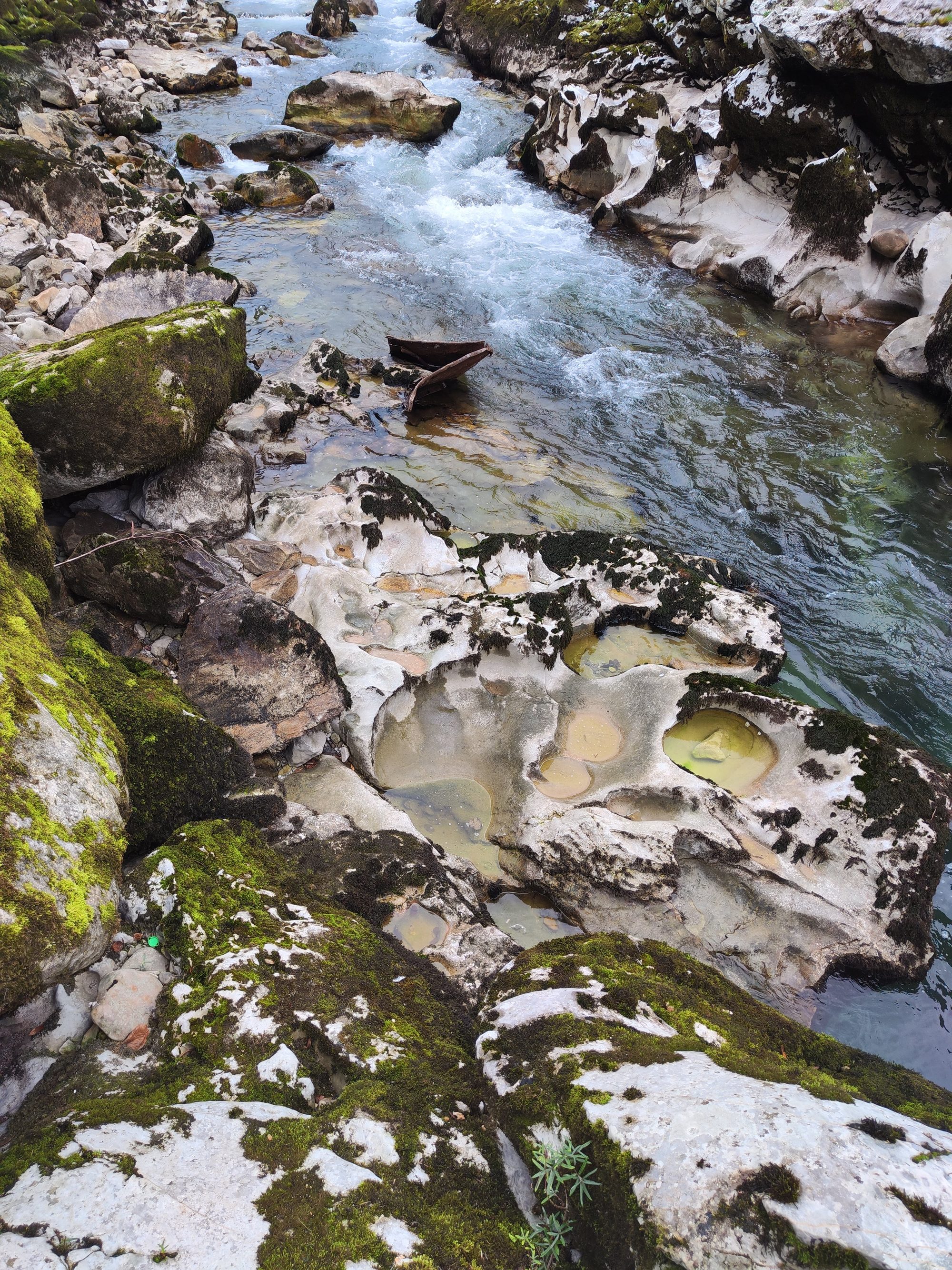 Río de aguas cristalinas fluyendo entre rocas calizas erosionadas con musgo verde.