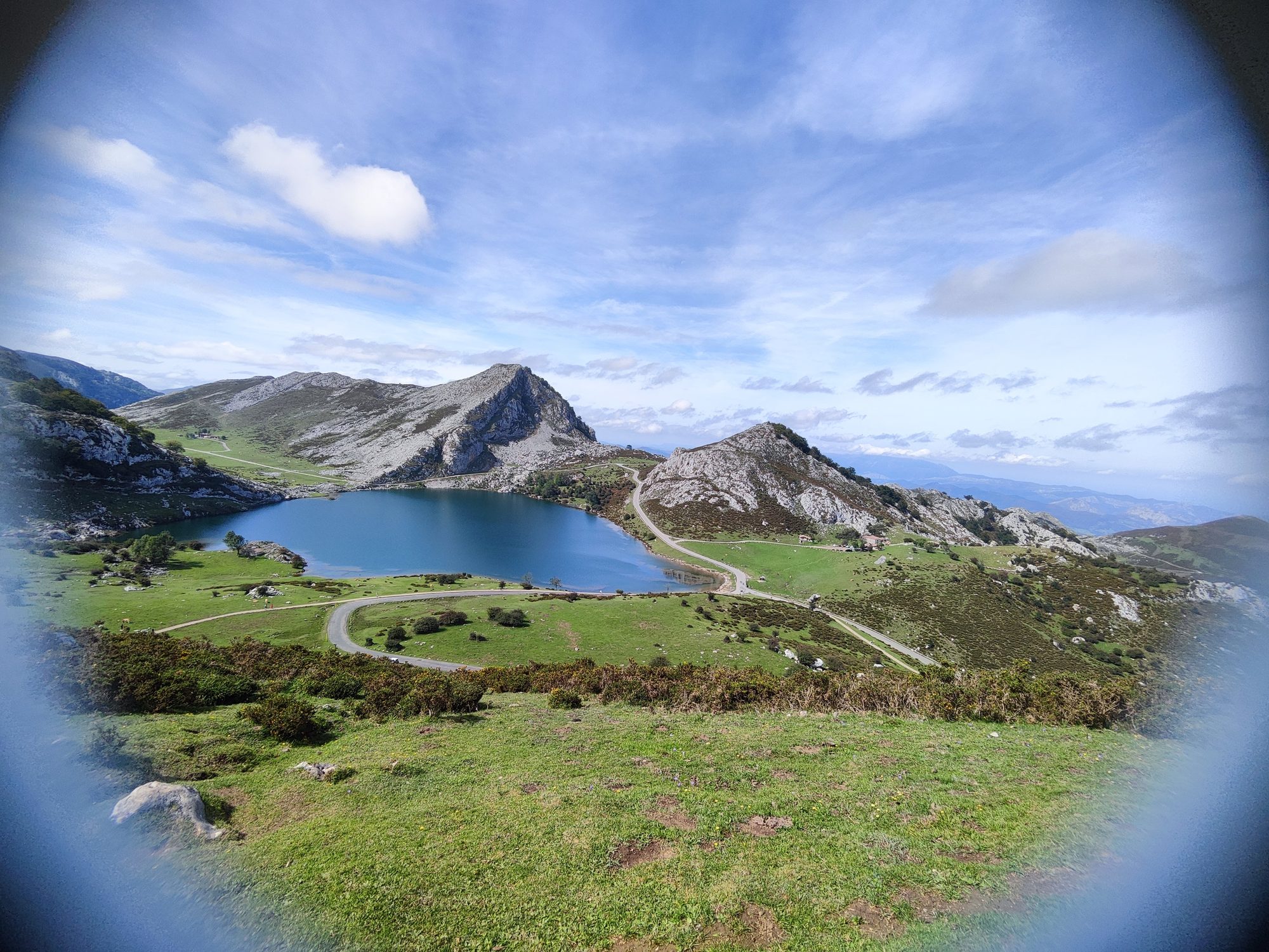 Lago Enol de aguas azules rodeado de montañas rocosas y verdes praderas asturianas.