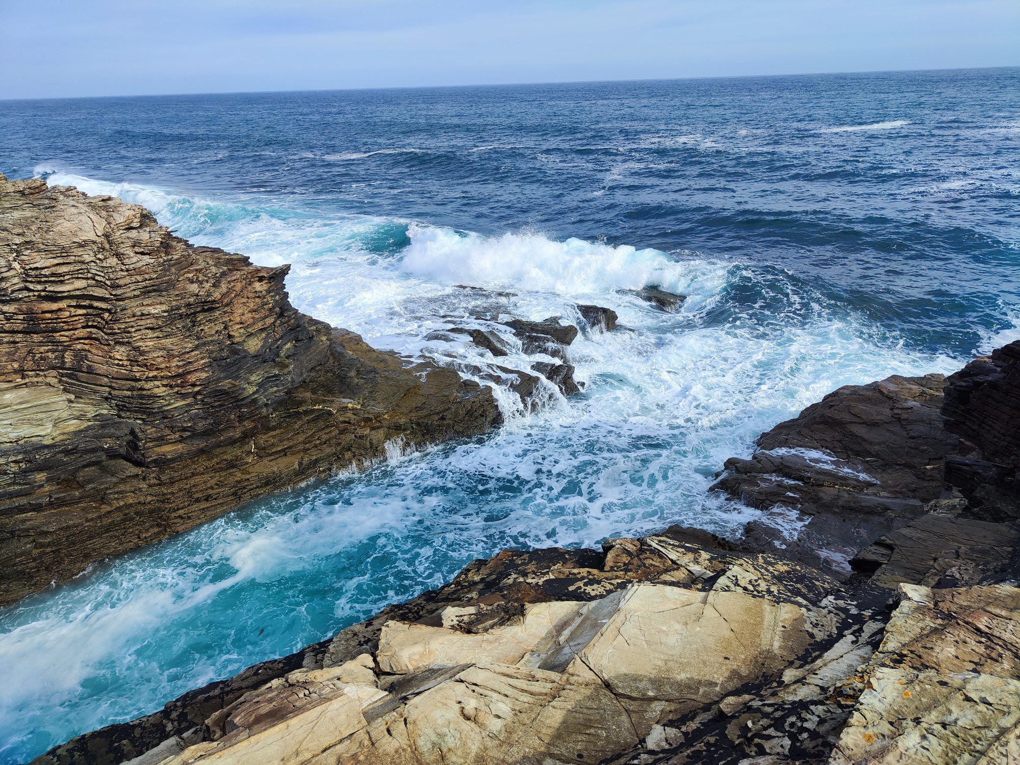 Olas del mar Cantábrico rompiendo contra escarpados acantilados rocosos en la costa.