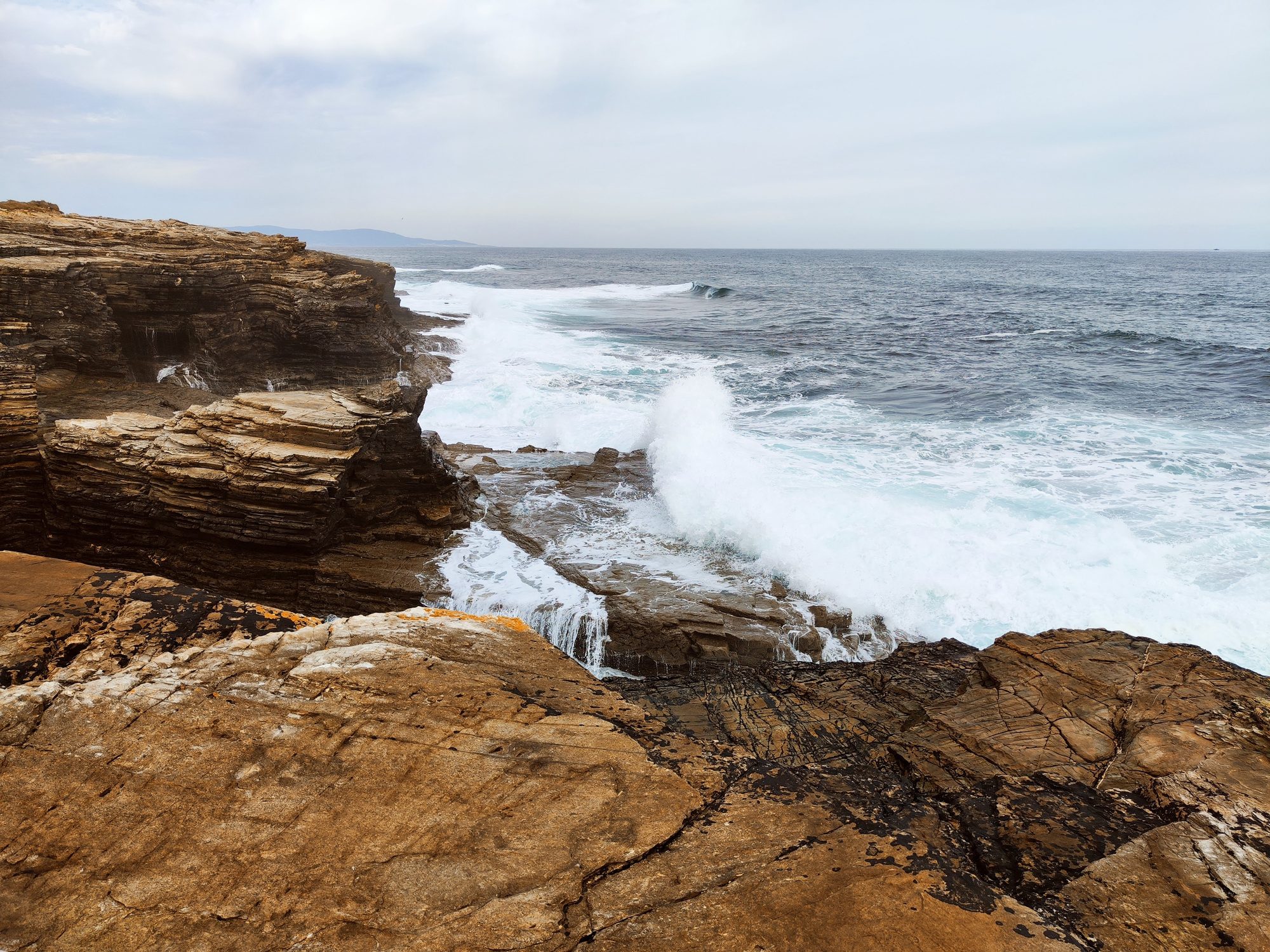Olas del mar rompiendo con fuerza contra los acantilados rocosos de la costa.