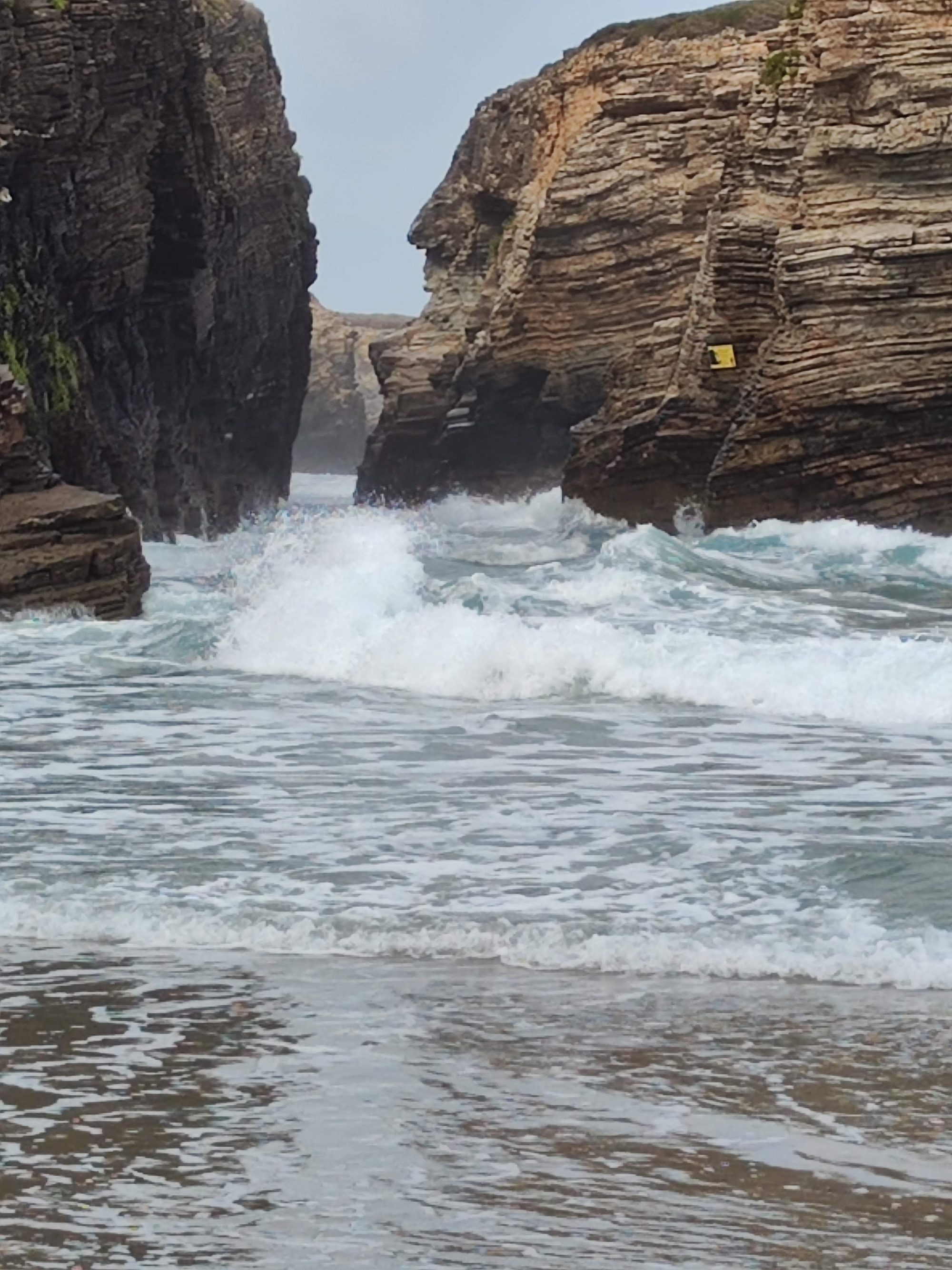 Olas del mar rompiendo con fuerza entre acantilados rocosos en la costa.