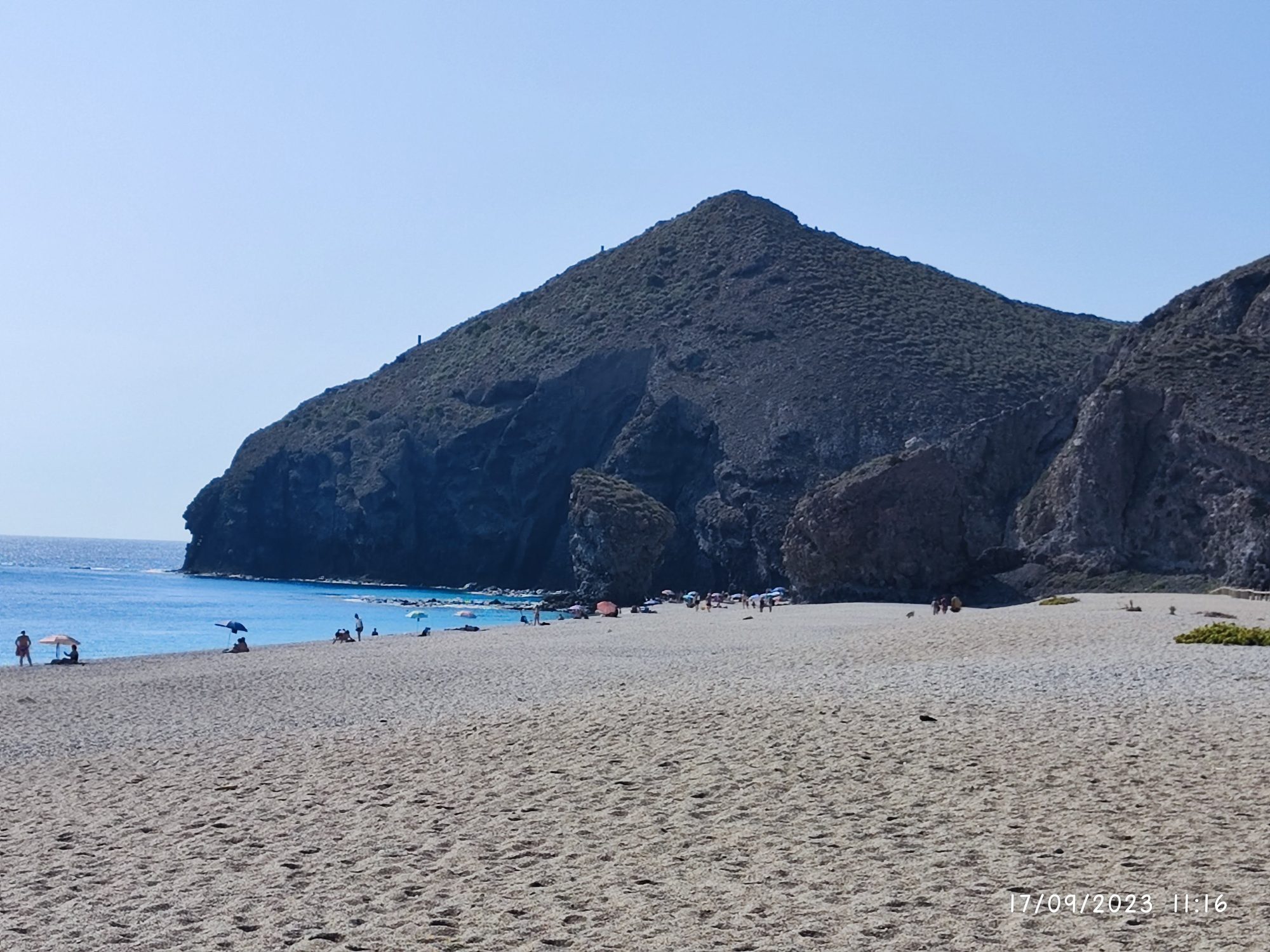 Playa de arena clara y aguas turquesas junto a imponentes acantilados rocosos en Carboneras.
