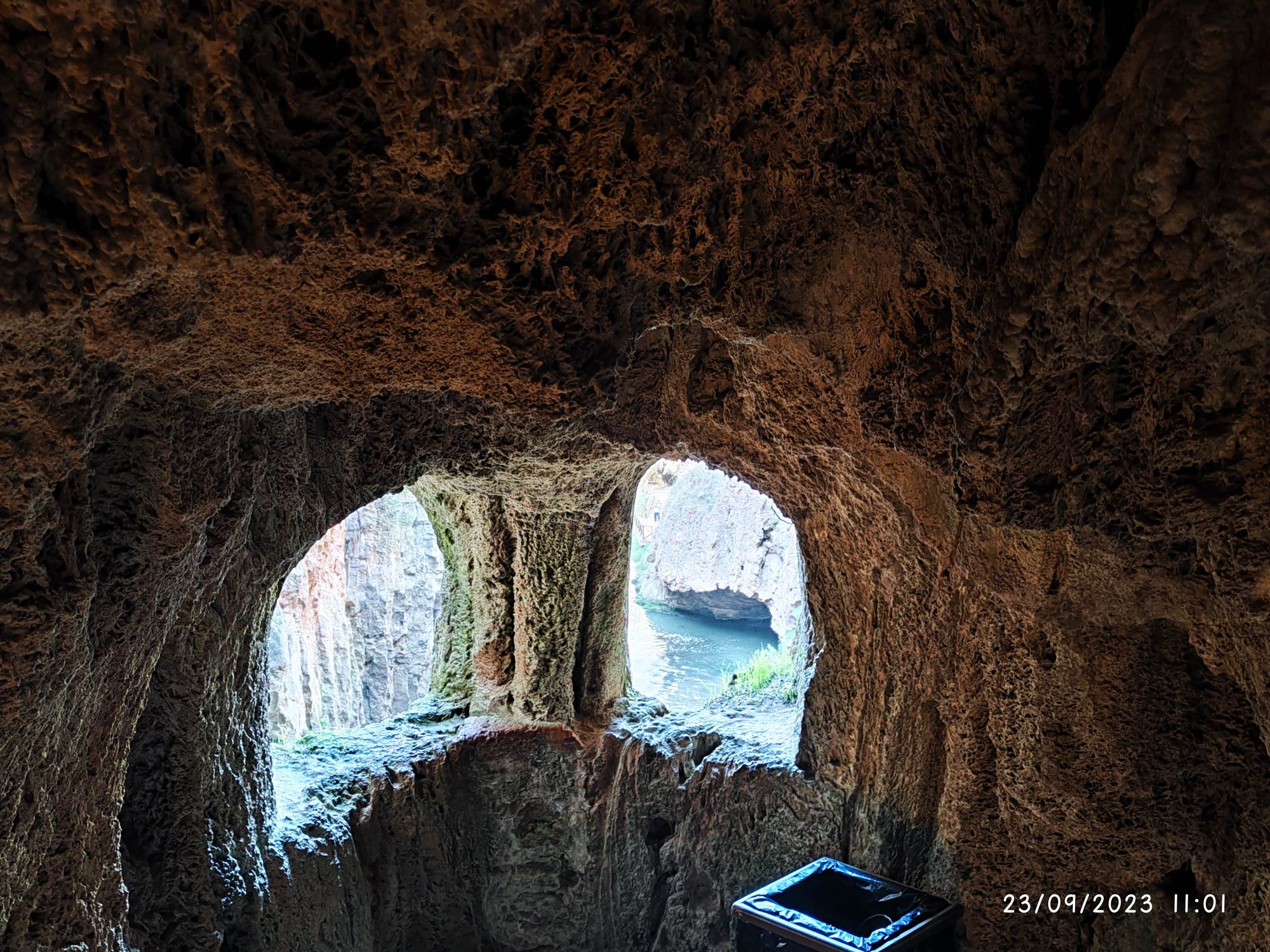 Vista desde el interior de una cueva de roca hacia el agua y los acantilados.