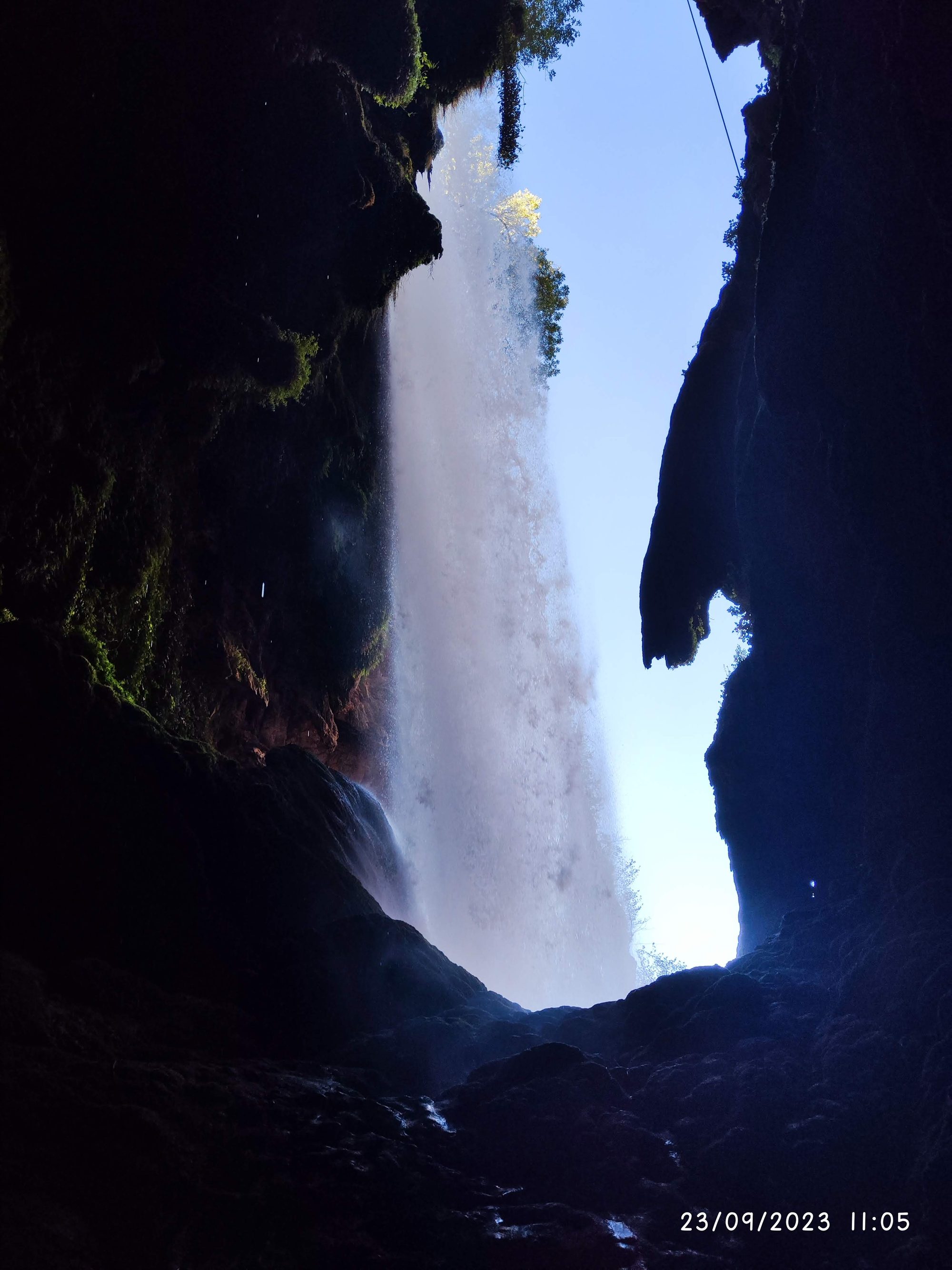 Impresionante cascada vista desde el interior sombrío de una cueva rocosa.