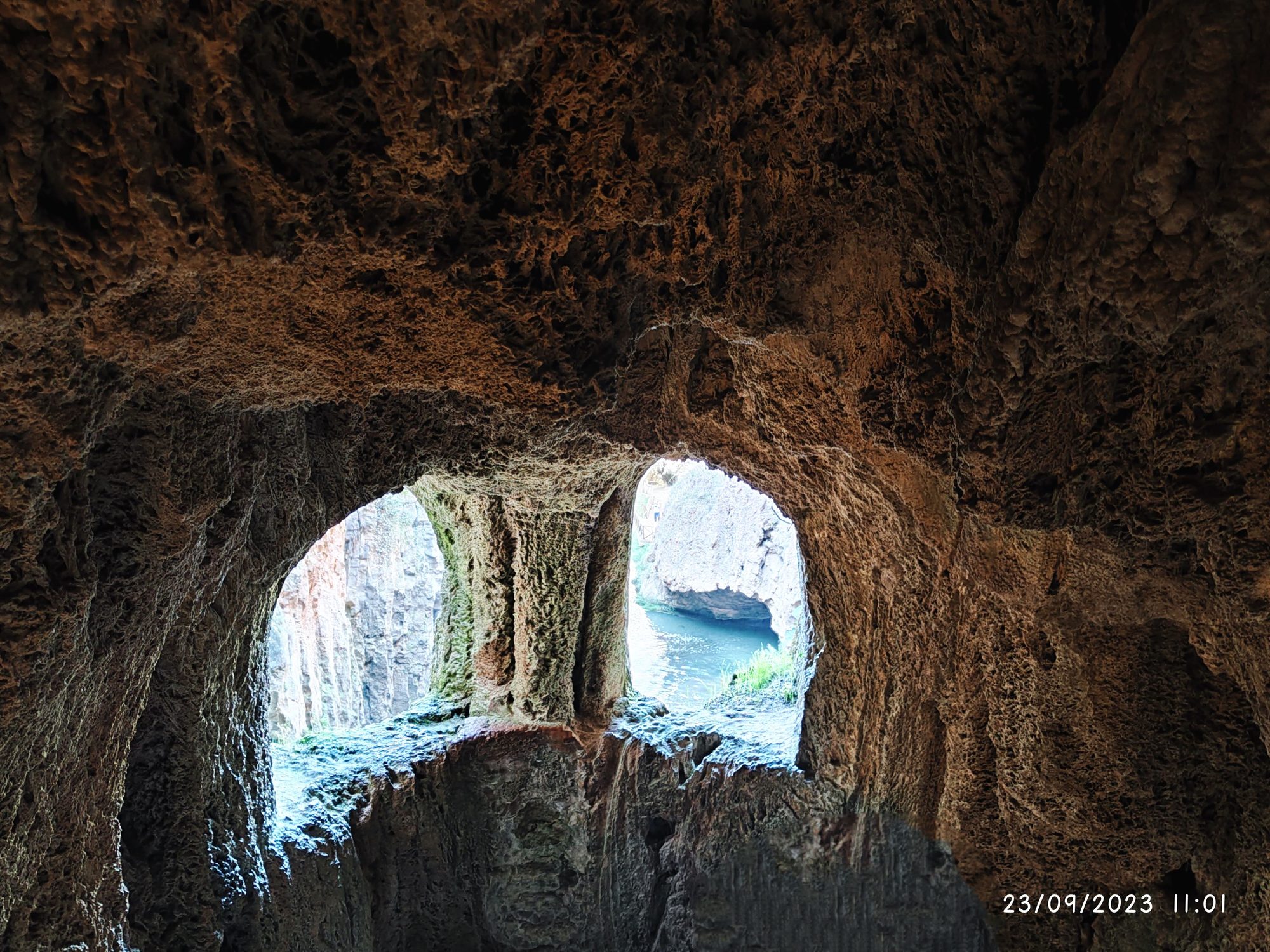 Vista desde el interior de una cueva de piedra hacia el agua y acantilados exteriores.