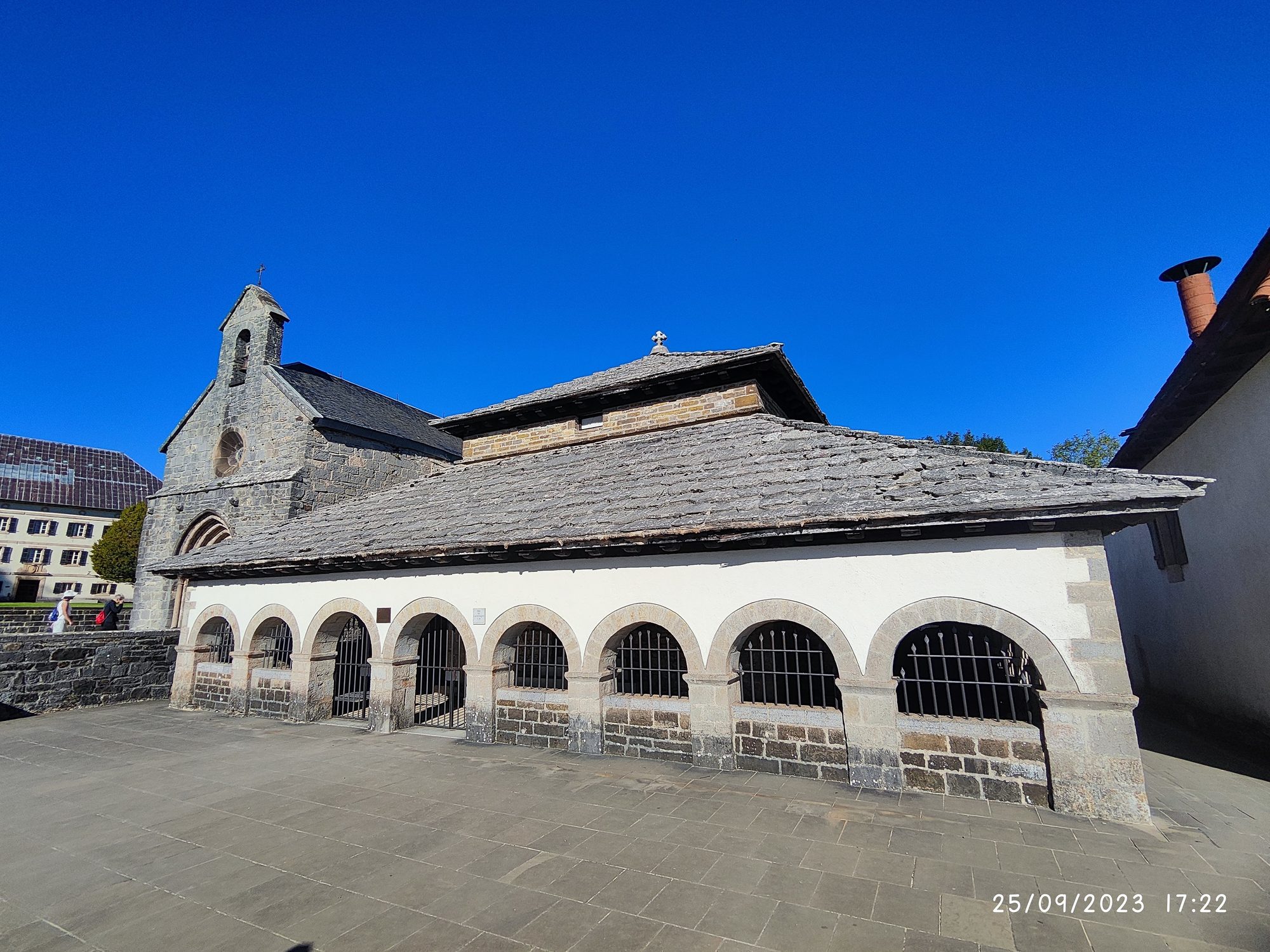 Capilla de piedra histórica con tejado de lajas en Roncesvalles bajo un cielo azul.