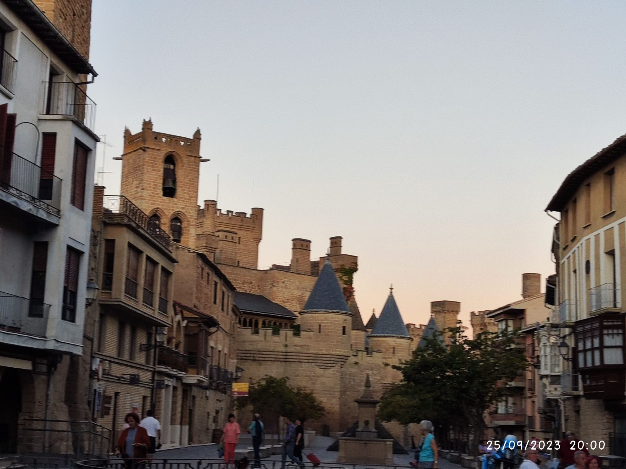 Castillo medieval de Olite con murallas y torres cónicas bajo la luz del atardecer.